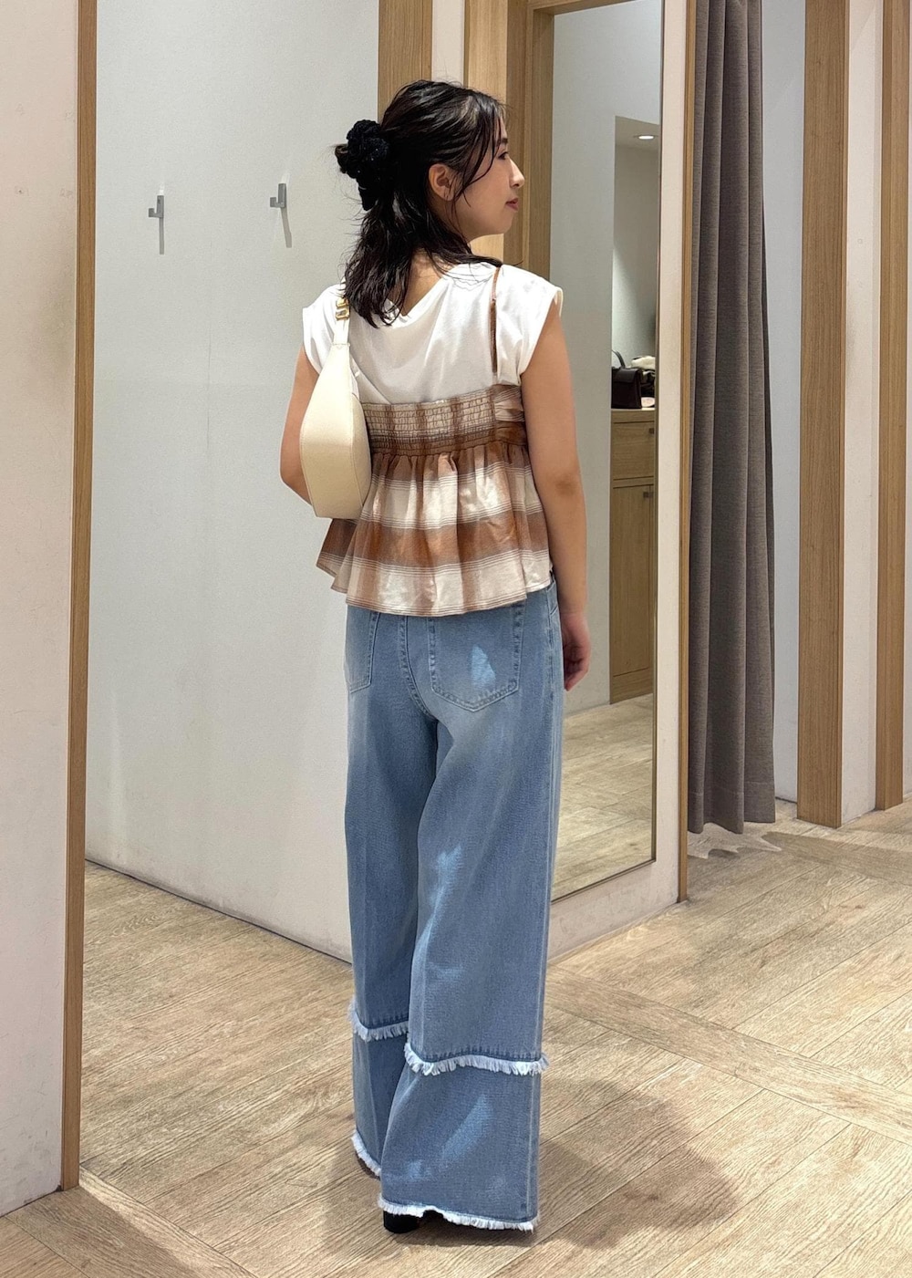 ブラック系のサンダル、ホワイト系のショルダーバッグ、ブルー系のデニムパンツを着用したレディースの夏コーディネートの3枚目の写真