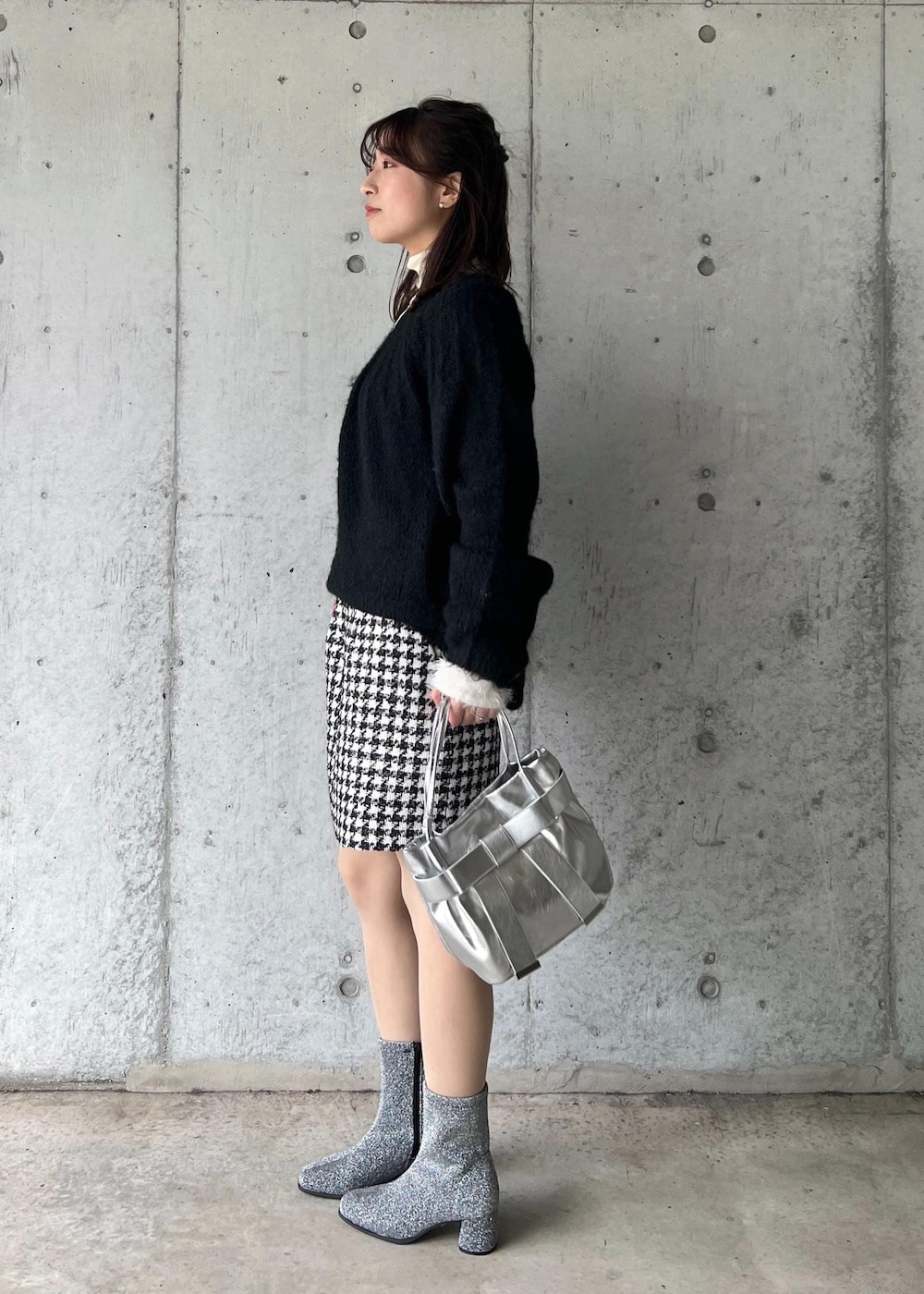 シルバー系のブーツ、ブラック系のスカート、ホワイト系のニット/セーターを着用したレディースの冬コーディネートの3枚目の写真