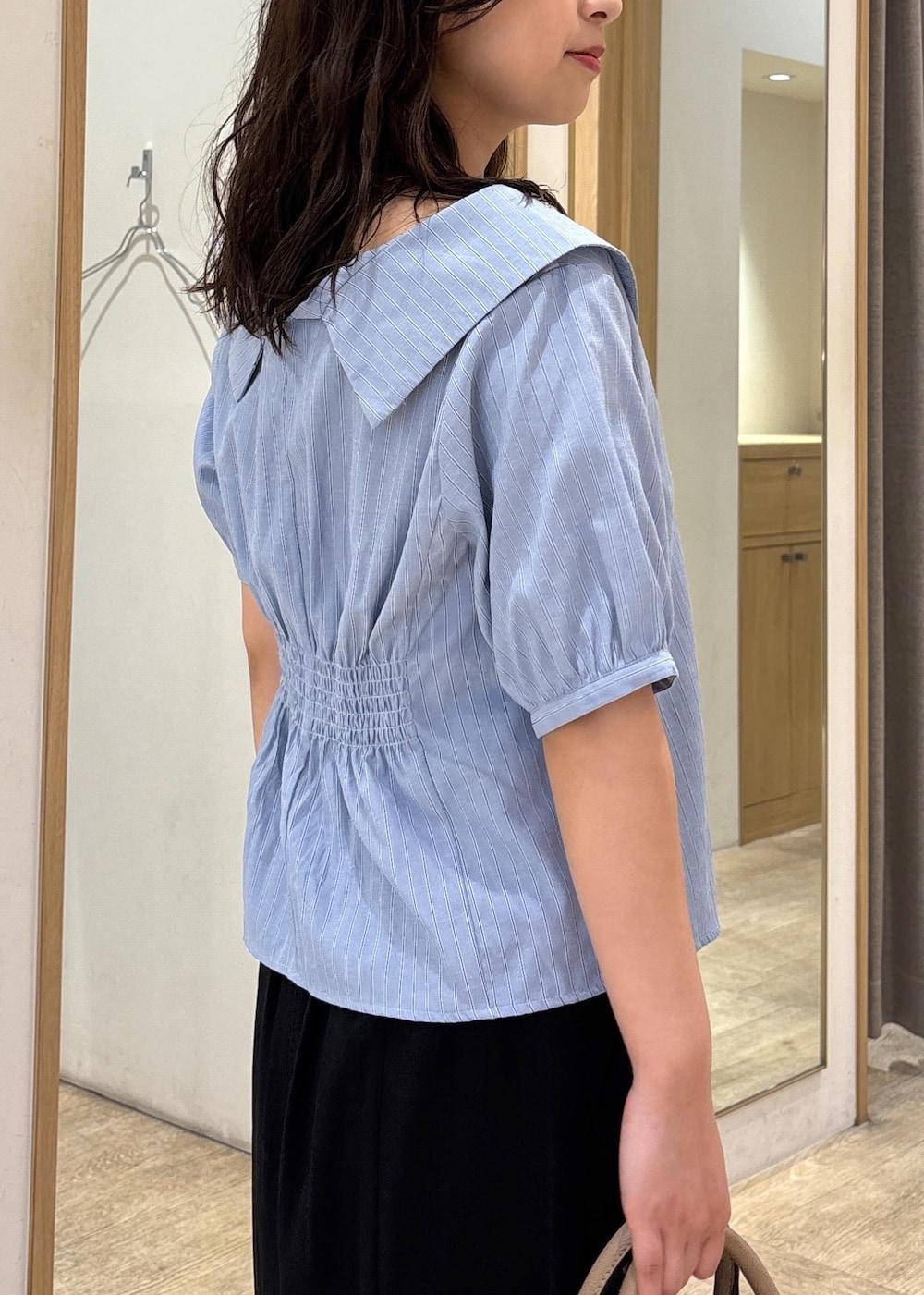 ベージュ系のボストンバッグ、ブラック系のスカート、ブラック系のローファーを着用したレディースの秋コーディネートの6枚目の写真