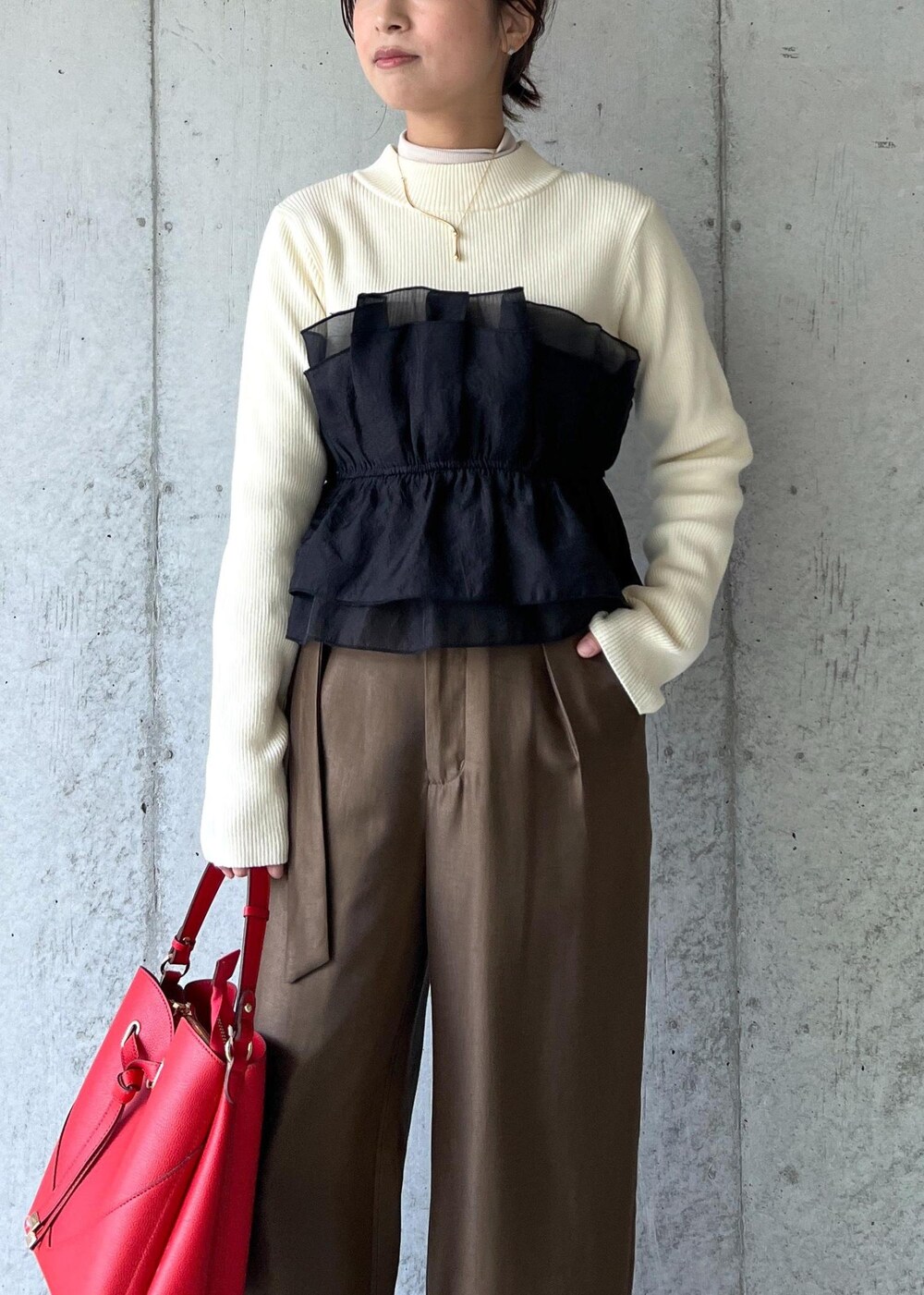 レッド系のショルダーバッグ、ブラック系のパンプス、ホワイト系のニット/セーターを着用したレディースの冬コーディネートの5枚目の写真