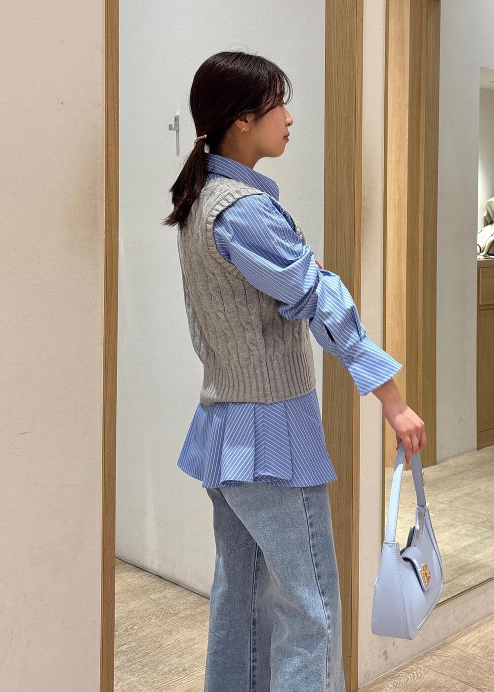 ブルー系のシャツ/ブラウス、グレー系のベスト、ブルー系のデニムパンツを着用したレディースの冬コーディネートの7枚目の写真