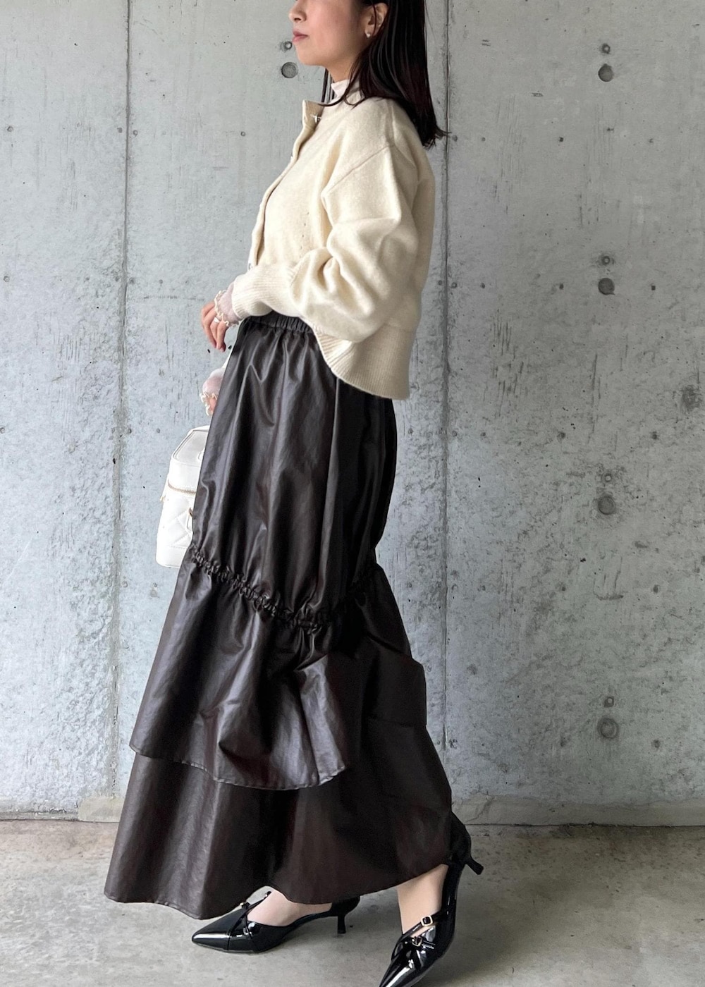 ブラウン系のスカート、ベージュ系のTシャツ/カットソー、ブラック系のパンプスを着用したレディースの冬コーディネートの3枚目の写真