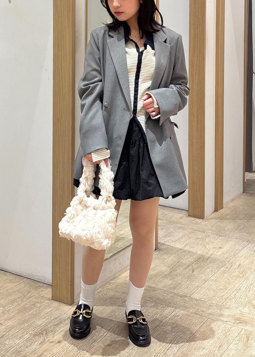 グレー系のテーラードジャケット、ブラック系のローファー、ブラック系のスカートを着用したレディースの春コーディネートの2枚目の写真