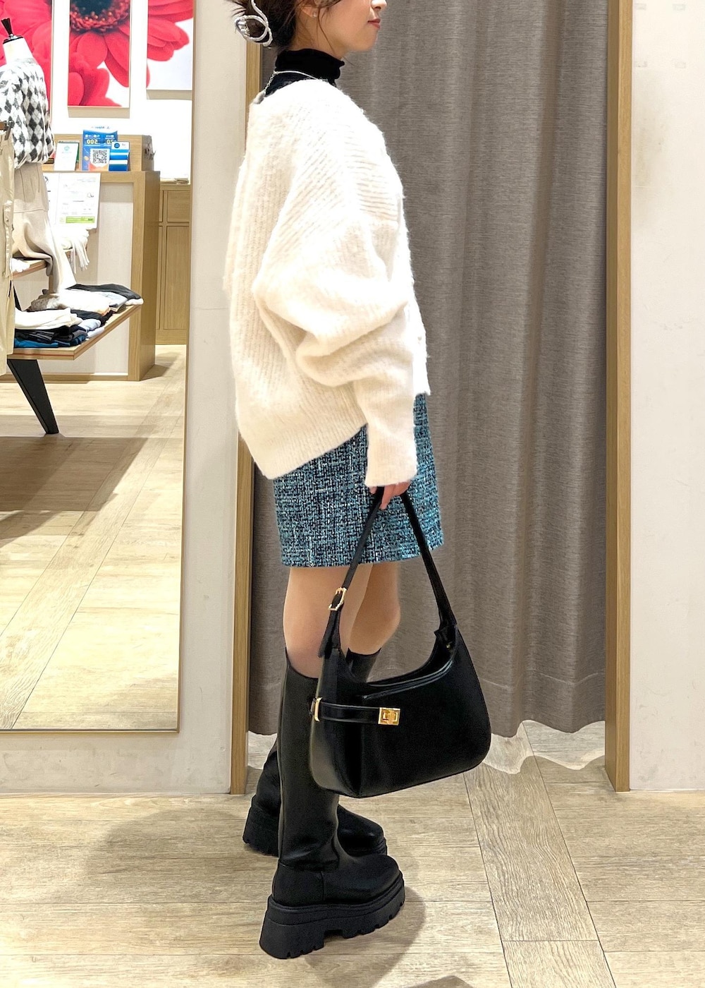 ブラック系のブーツ、ブルー系のスカート、ホワイト系のカーディガン/ボレロを着用したレディースの冬コーディネートの4枚目の写真