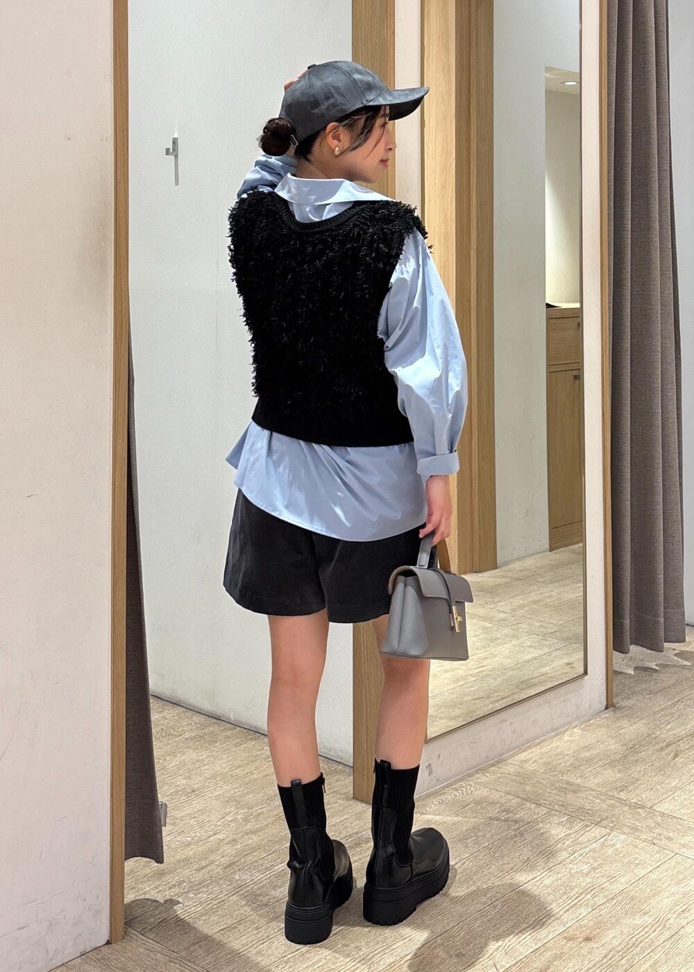 グレー系のショルダーバッグ、ブルー系のシャツ/ブラウス、ブラック系のベストを着用したレディースの秋コーディネートの3枚目の写真