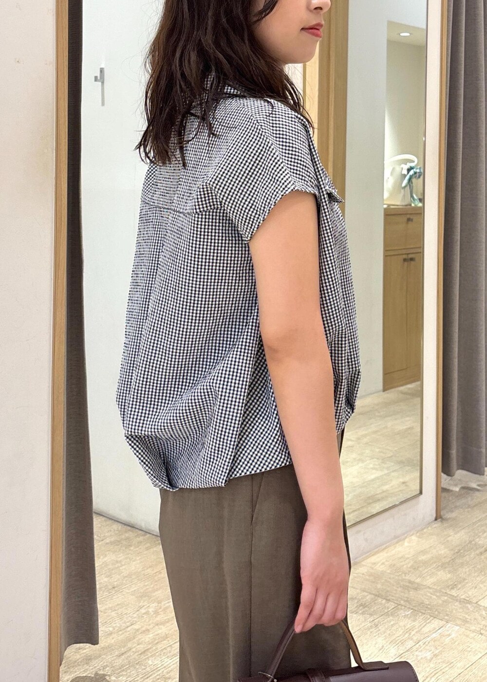 ブラウン系のショルダーバッグ、グリーン系のスラックス、ブラック系のシャツ/ブラウスを着用したレディースの夏コーディネートの5枚目の写真