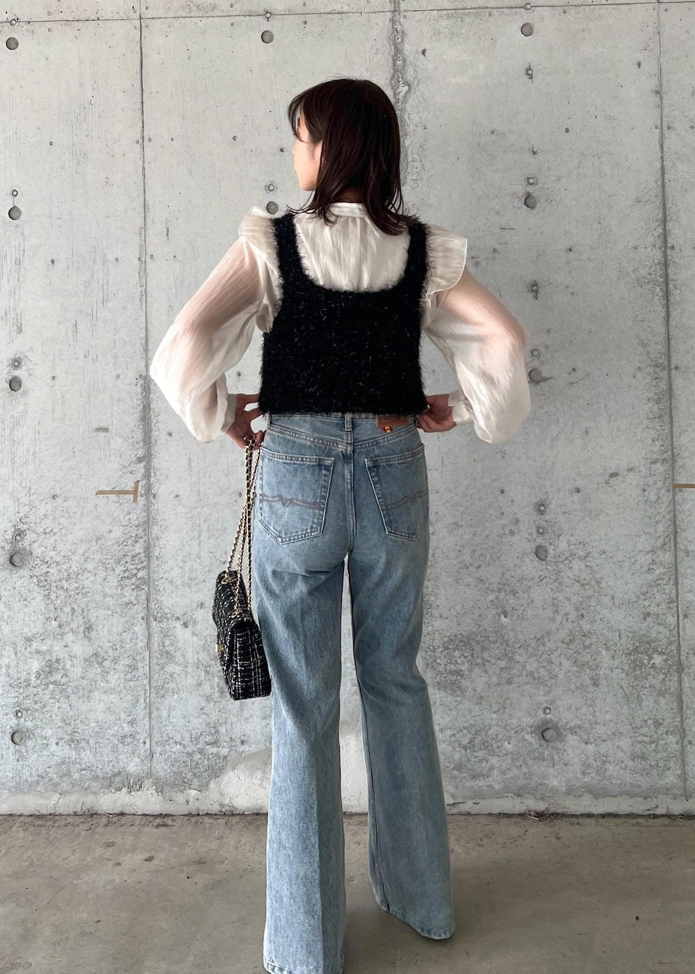 ブルー系のデニムパンツ、ブラック系のキャミソール、シルバー系のブーツを着用したレディースの秋コーディネートの5枚目の写真