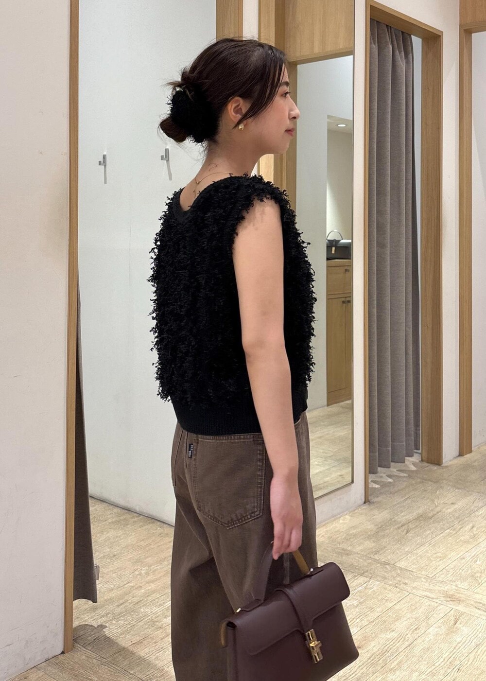 ブラウン系のショルダーバッグ、ブラック系のパンプス、ブラック系のベストを着用したレディースの秋コーディネートの5枚目の写真