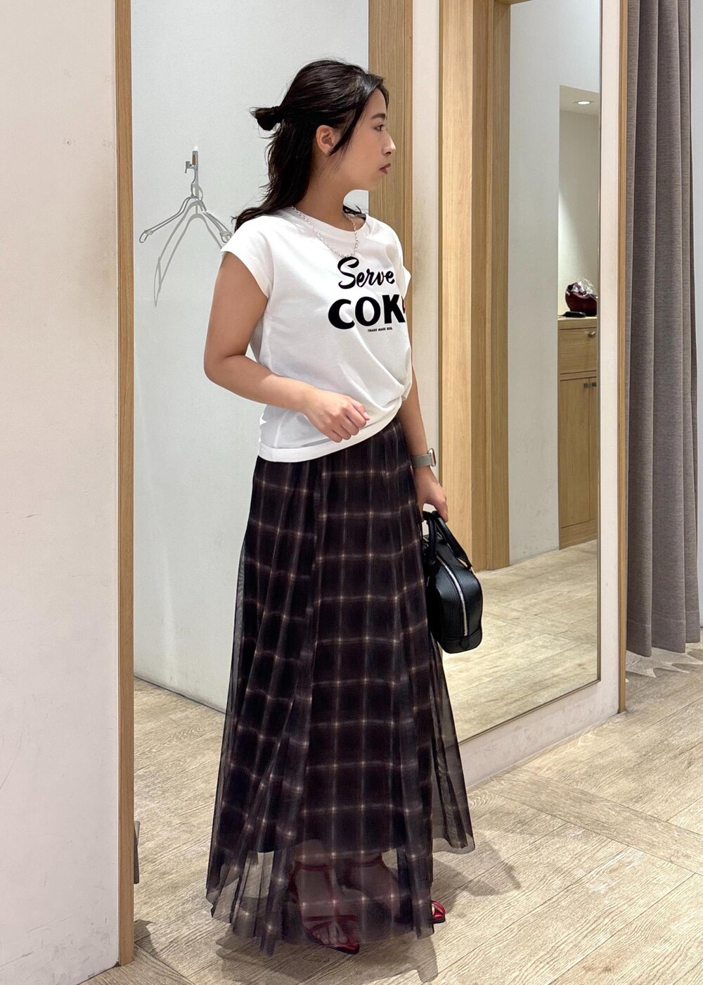 レッド系のサンダル、ブラック系のショルダーバッグ、ブラウン系のスカートを着用したレディースの夏コーディネートの4枚目の写真