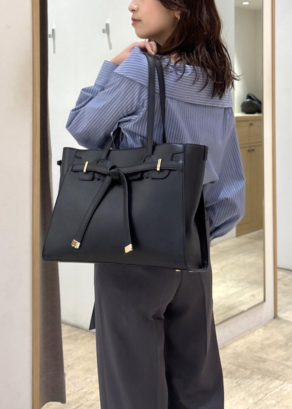 ブラック系のトートバッグ、ブラック系のパンプス、ブルー系のシャツ/ブラウスを着用したレディースの秋コーディネートの6枚目の写真