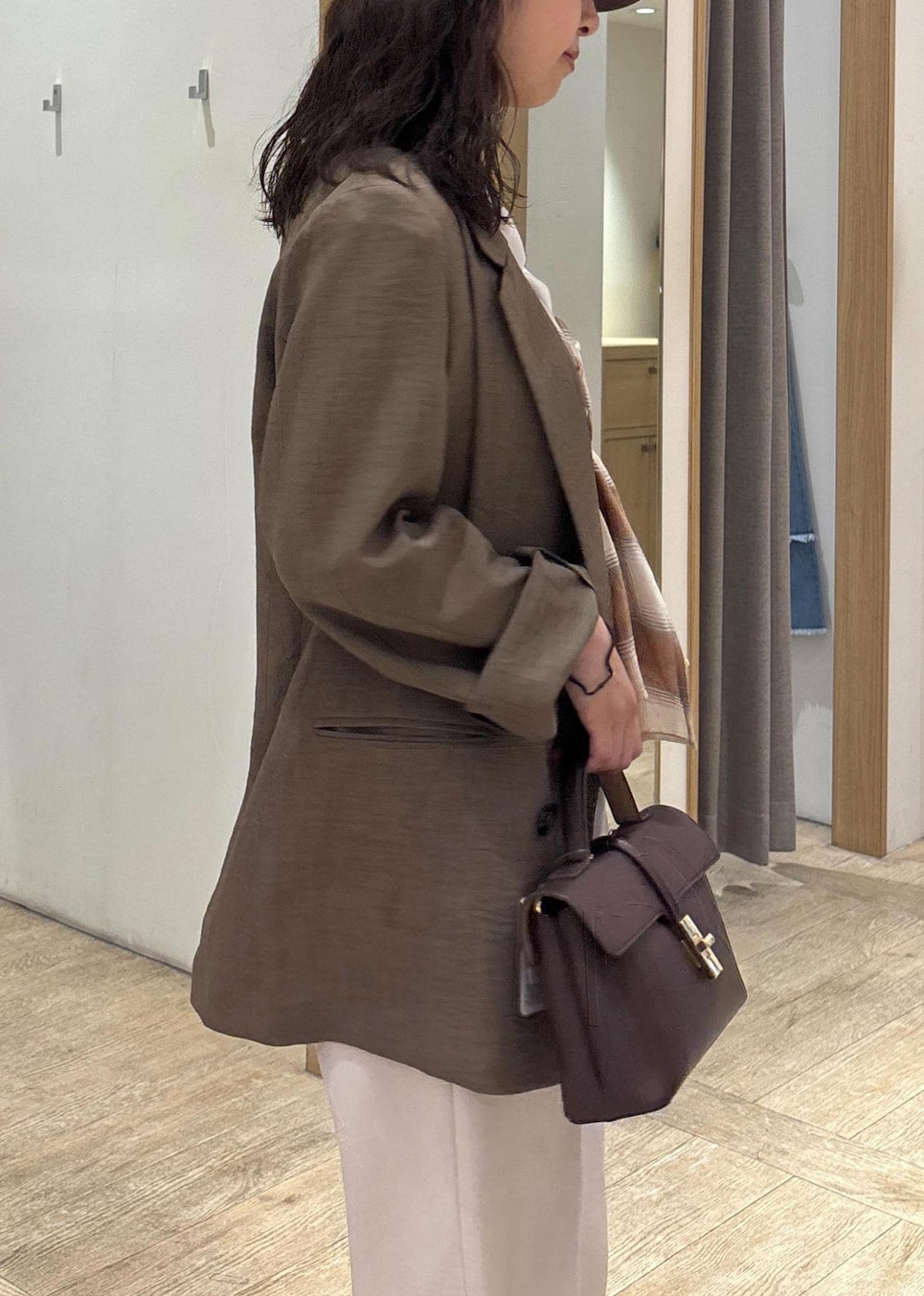 ブラウン系のショルダーバッグ、グリーン系のテーラードジャケット、ホワイト系のスラックスを着用したレディースの夏コーディネートの7枚目の写真