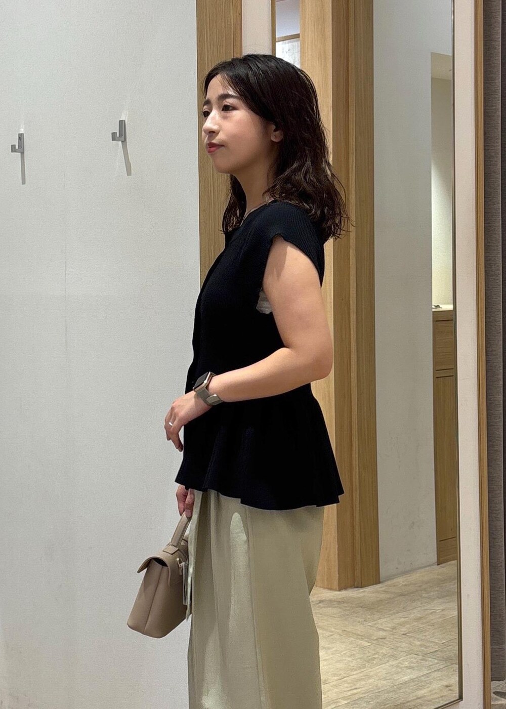 ベージュ系のショルダーバッグ、ブラック系のパンプス、グリーン系のスラックスを着用したレディースの夏コーディネートの6枚目の写真