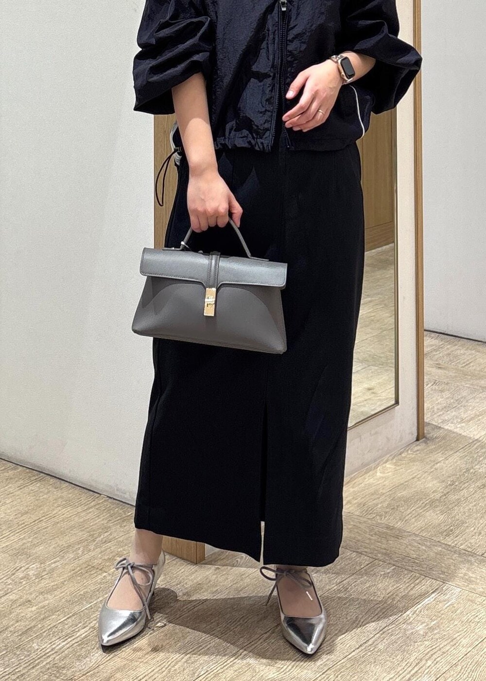 グレー系のショルダーバッグ、ブルー系のスカート、シルバー系のパンプスを着用したレディースの春コーディネートの9枚目の写真