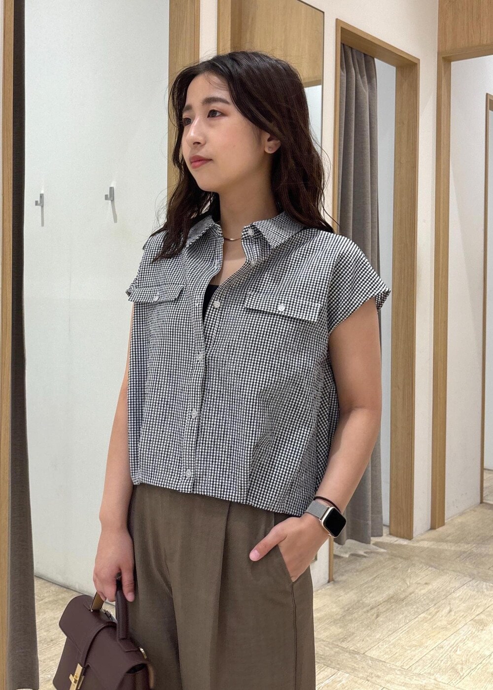 ブラウン系のショルダーバッグ、グリーン系のスラックス、ブラック系のシャツ/ブラウスを着用したレディースの夏コーディネートの7枚目の写真