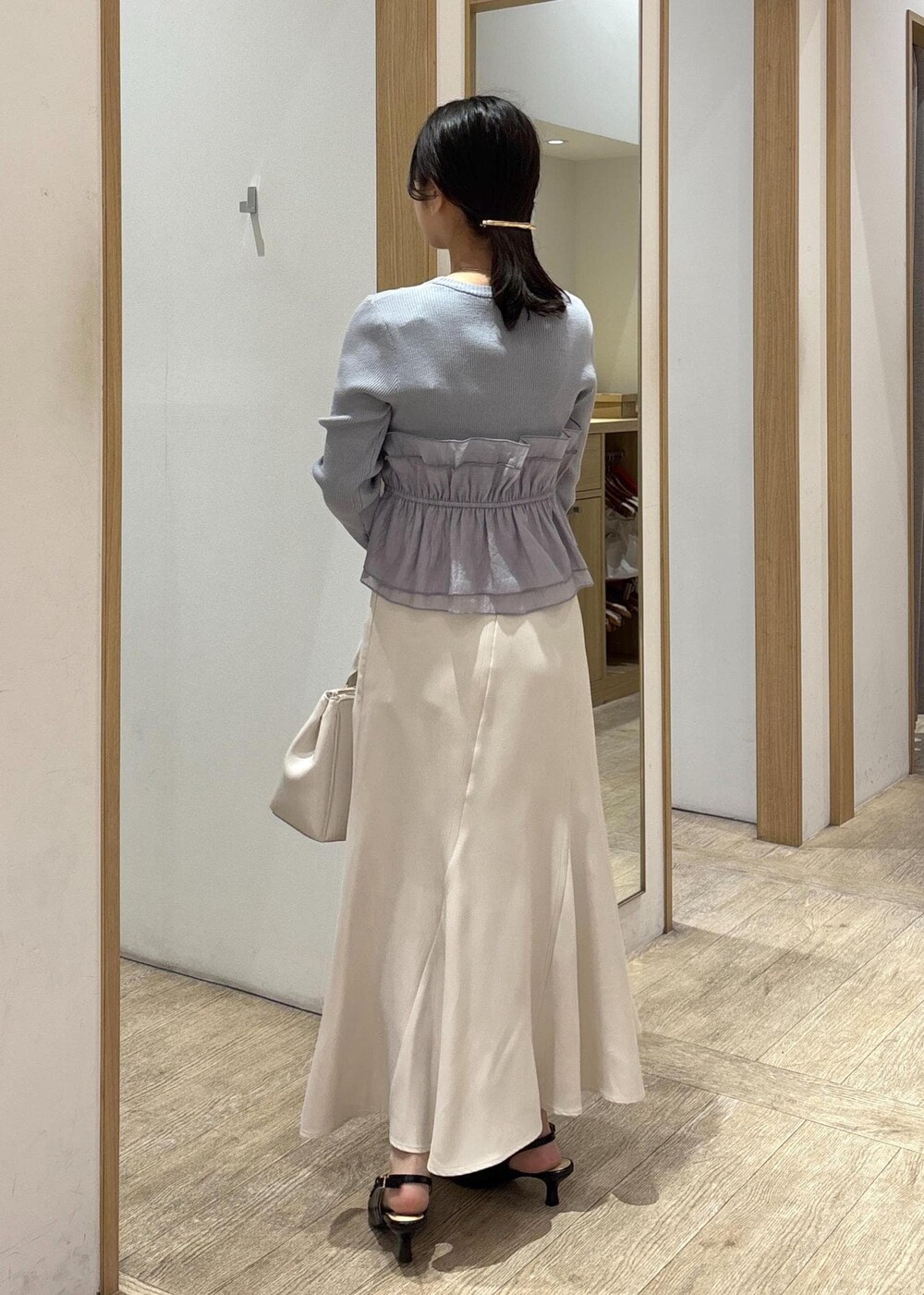 ブラック系のパンプス、ベージュ系のスカート、ブルー系のニット/セーターを着用したレディースの春コーディネートの4枚目の写真