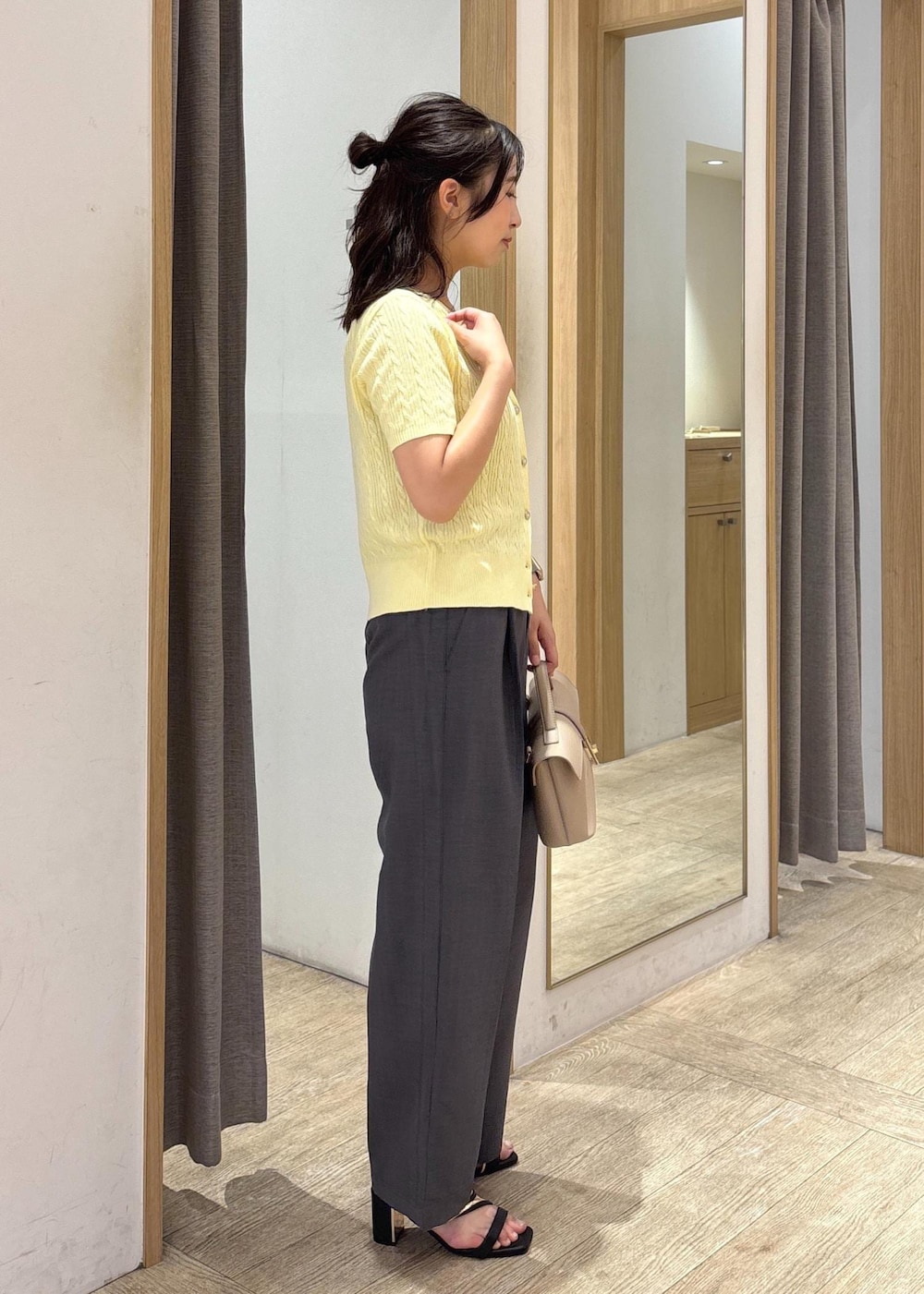 ベージュ系のショルダーバッグ、ブラック系のサンダル、グレー系のスラックスを着用したレディースの夏コーディネートの2枚目の写真