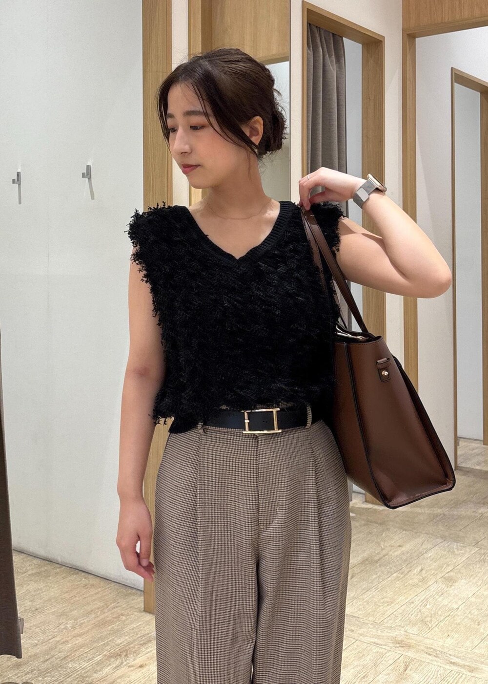 ブラック系のパンプス、ブラック系のベスト、ベージュ系のスラックスを着用したレディースの秋コーディネートの4枚目の写真