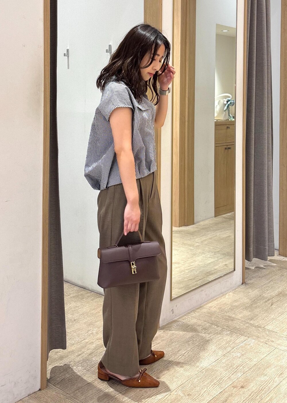 ブラウン系のショルダーバッグ、グリーン系のスラックス、ブラック系のシャツ/ブラウスを着用したレディースの夏コーディネートの2枚目の写真