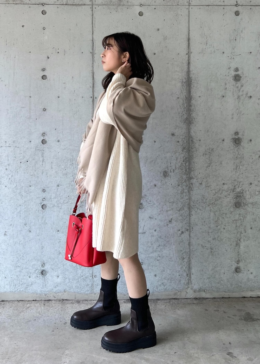 ブラウン系のブーツ、レッド系のショルダーバッグ、ホワイト系のワンピースを着用したレディースの冬コーディネートの3枚目の写真