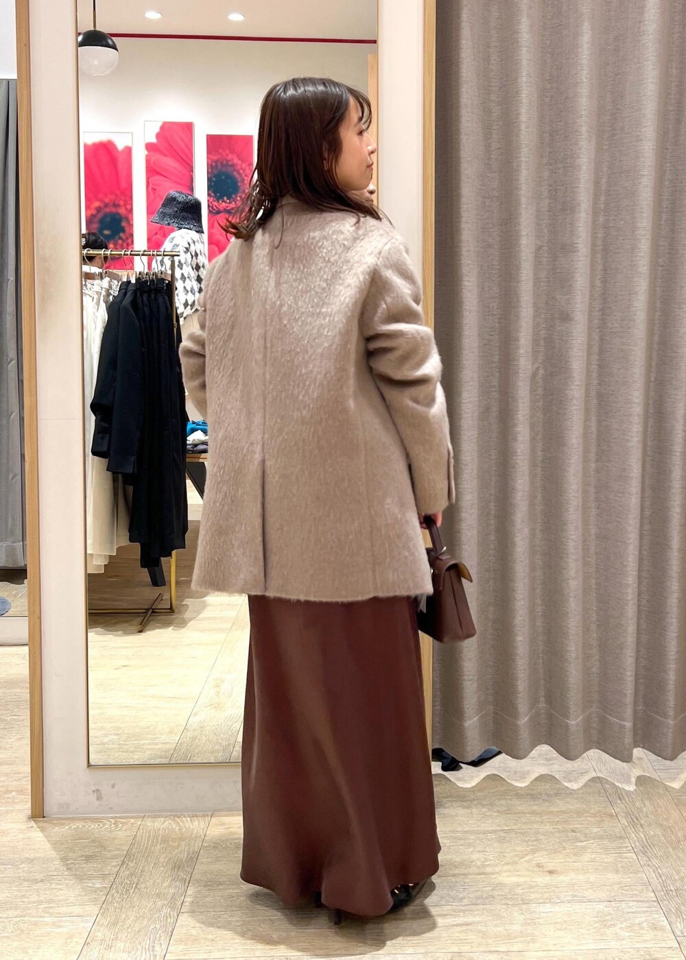 ブラック系のパンプス、ブラウン系のスカート、ホワイト系のニット/セーターを着用したレディースの冬コーディネートの3枚目の写真