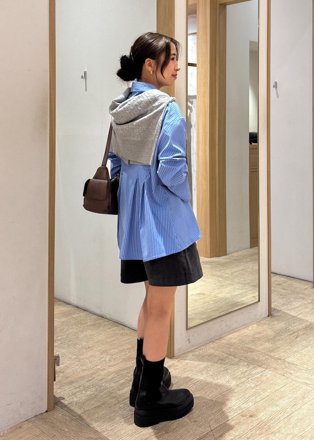 ブラック系のブーツ、ブルー系のシャツ/ブラウス、グレー系のカーディガン/ボレロを着用したレディースの秋コーディネートの3枚目の写真