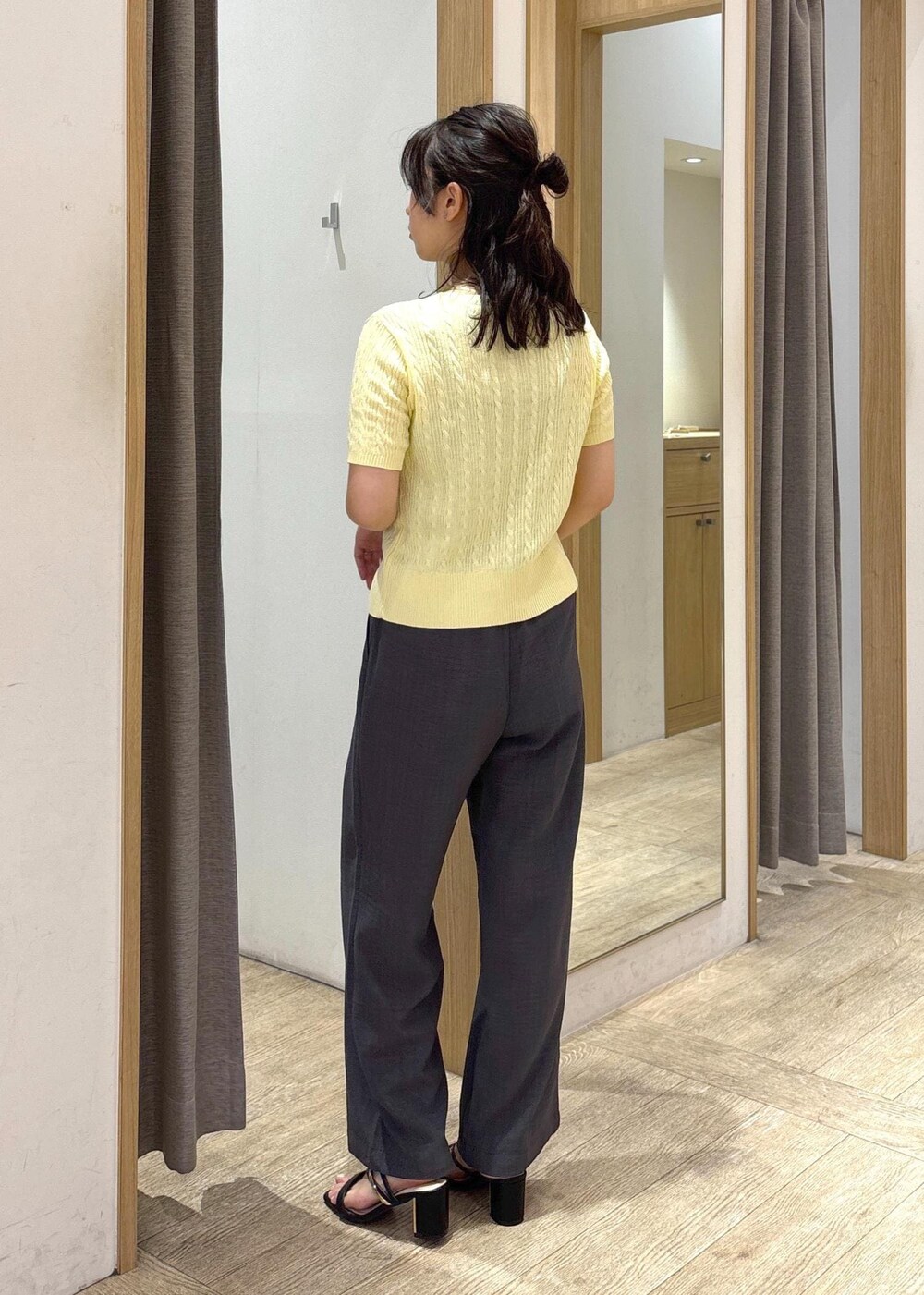 ベージュ系のショルダーバッグ、ブラック系のサンダル、グレー系のスラックスを着用したレディースの夏コーディネートの3枚目の写真