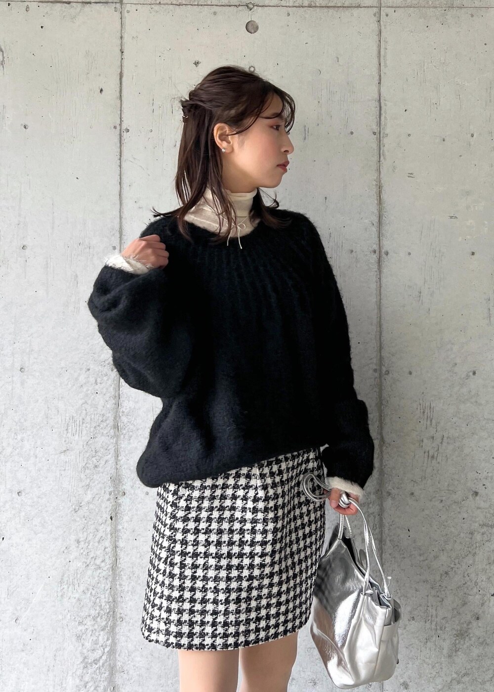 シルバー系のブーツ、ブラック系のスカート、ホワイト系のニット/セーターを着用したレディースの冬コーディネートの5枚目の写真