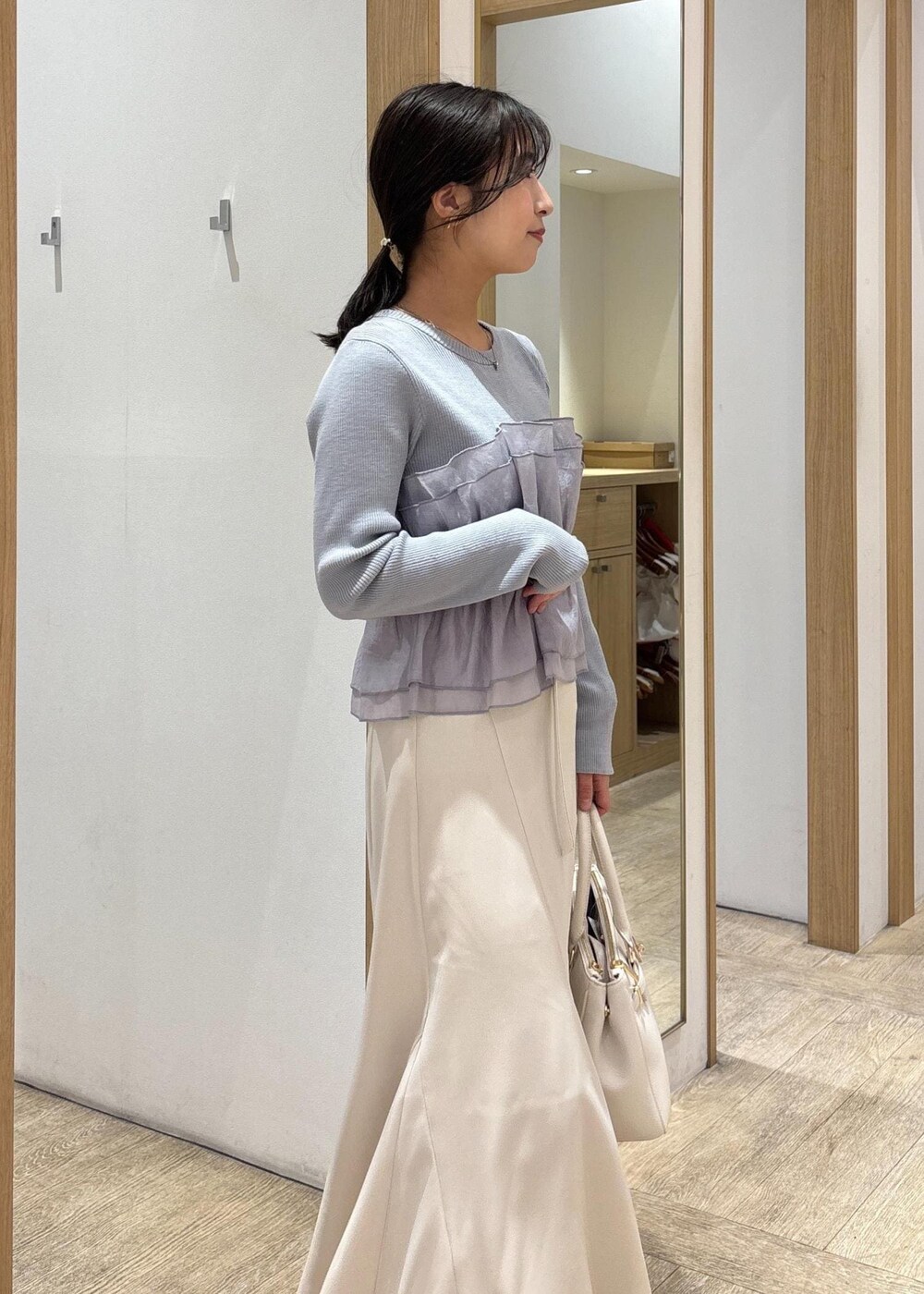 ブラック系のパンプス、ベージュ系のスカート、ブルー系のニット/セーターを着用したレディースの春コーディネートの7枚目の写真