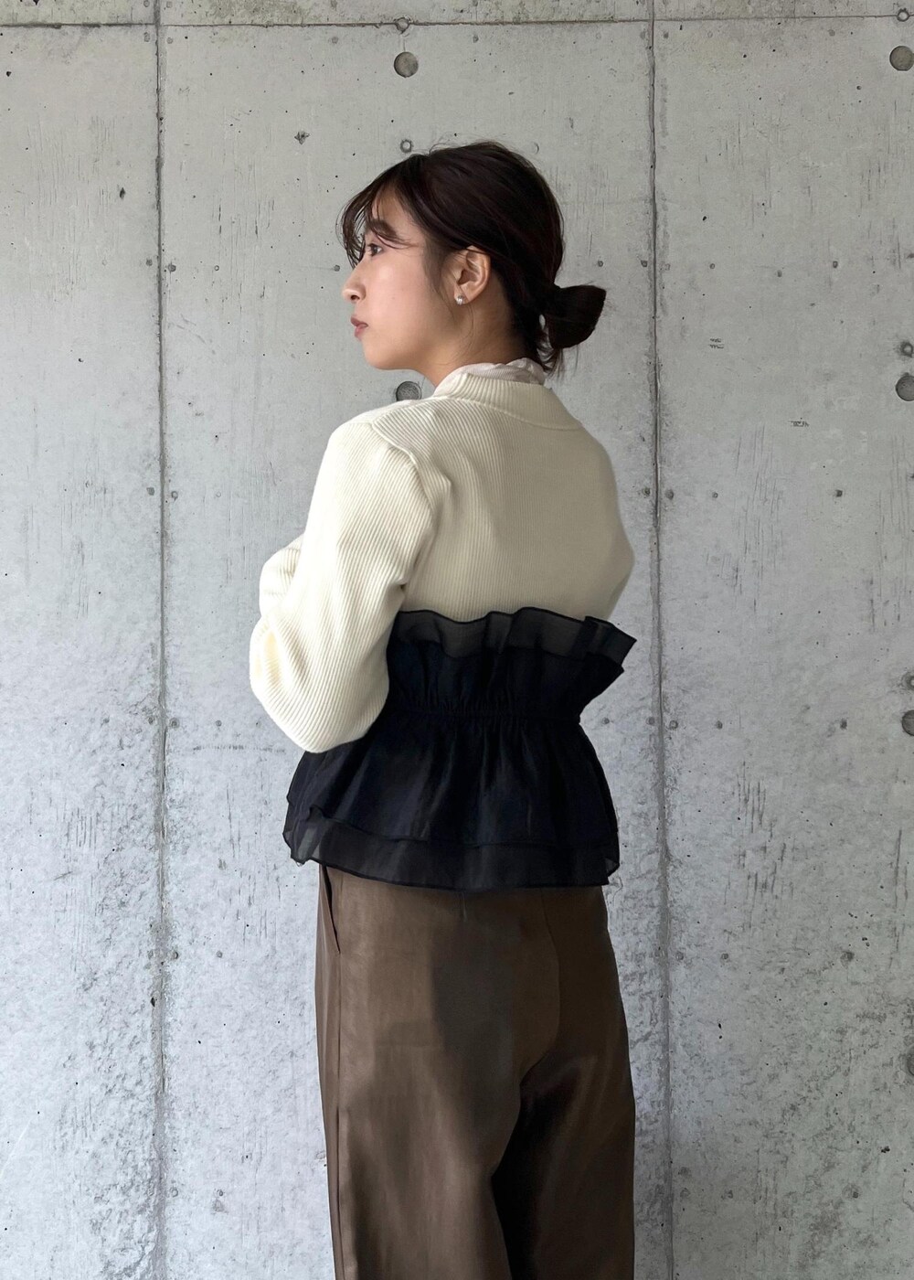 レッド系のショルダーバッグ、ブラック系のパンプス、ホワイト系のニット/セーターを着用したレディースの冬コーディネートの7枚目の写真