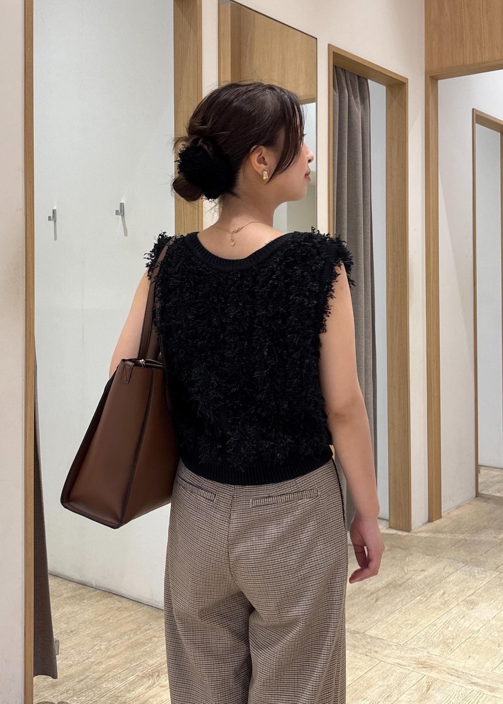 ブラック系のパンプス、ブラック系のベスト、ベージュ系のスラックスを着用したレディースの秋コーディネートの6枚目の写真