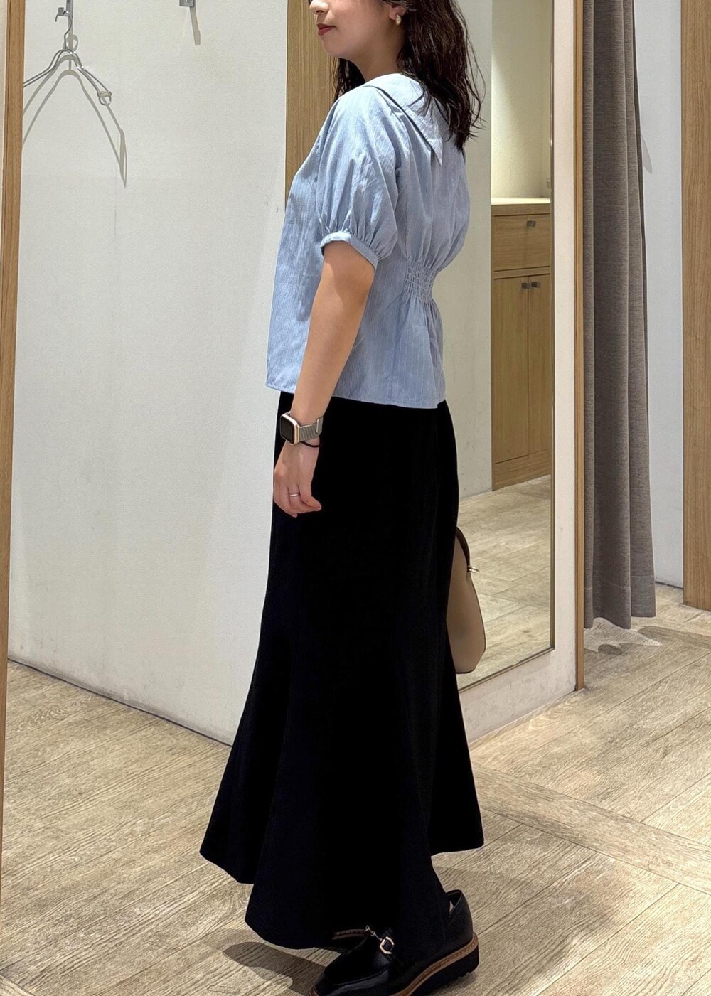 ベージュ系のボストンバッグ、ブラック系のスカート、ブラック系のローファーを着用したレディースの秋コーディネートの2枚目の写真