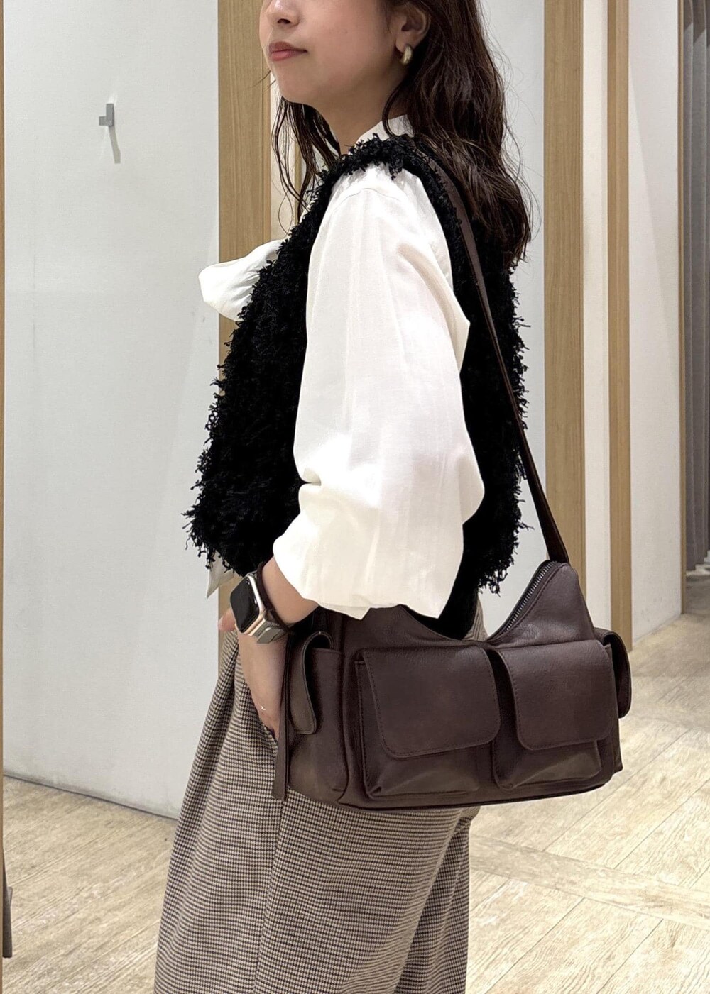 ベージュ系のスラックス、ブラウン系のショルダーバッグ、ブラック系のベストを着用したレディースの秋コーディネートの7枚目の写真