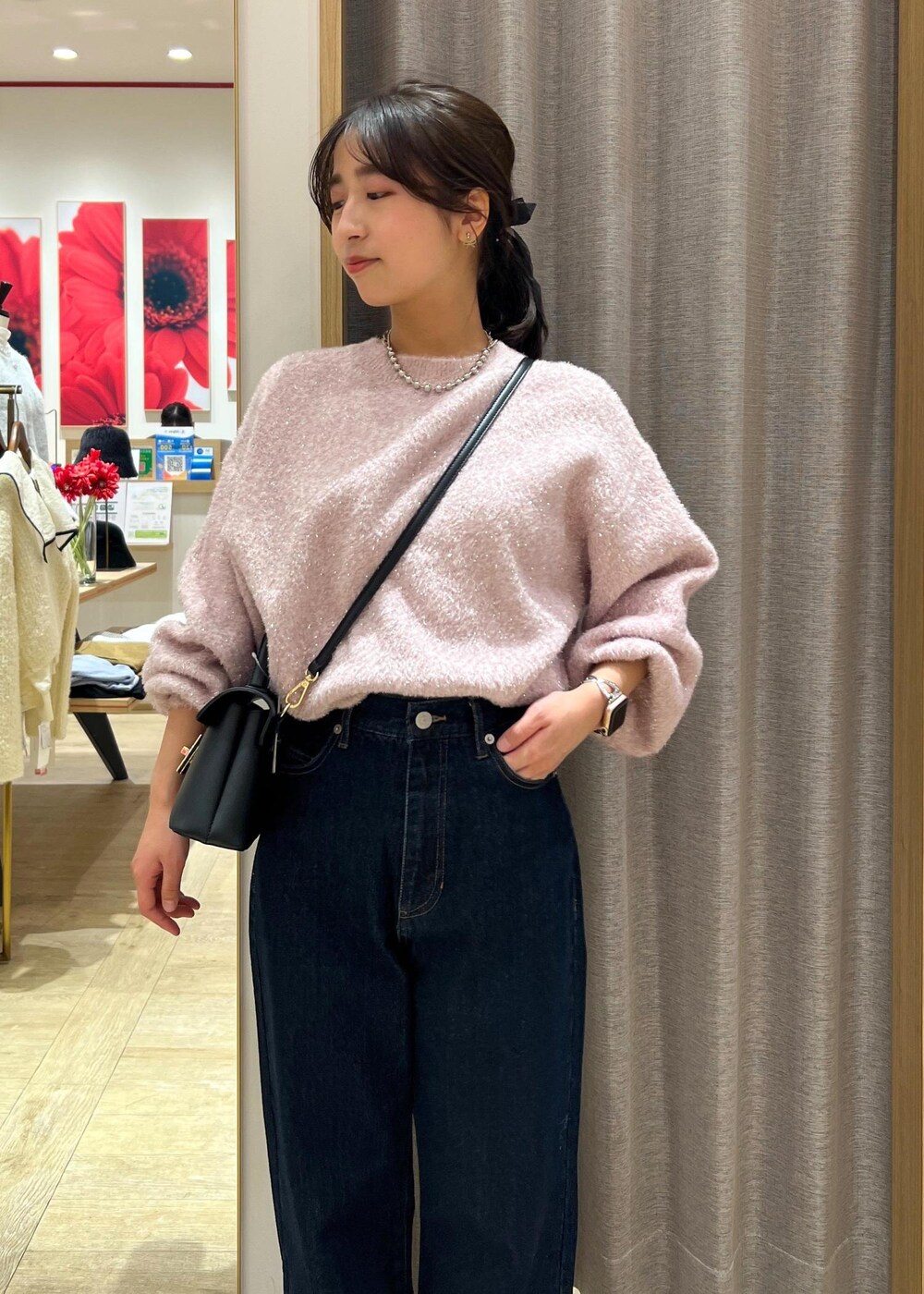 ブラック系のショルダーバッグ、シルバー系のブーツ、ブルー系のデニムパンツを着用したレディースの冬コーディネートの6枚目の写真