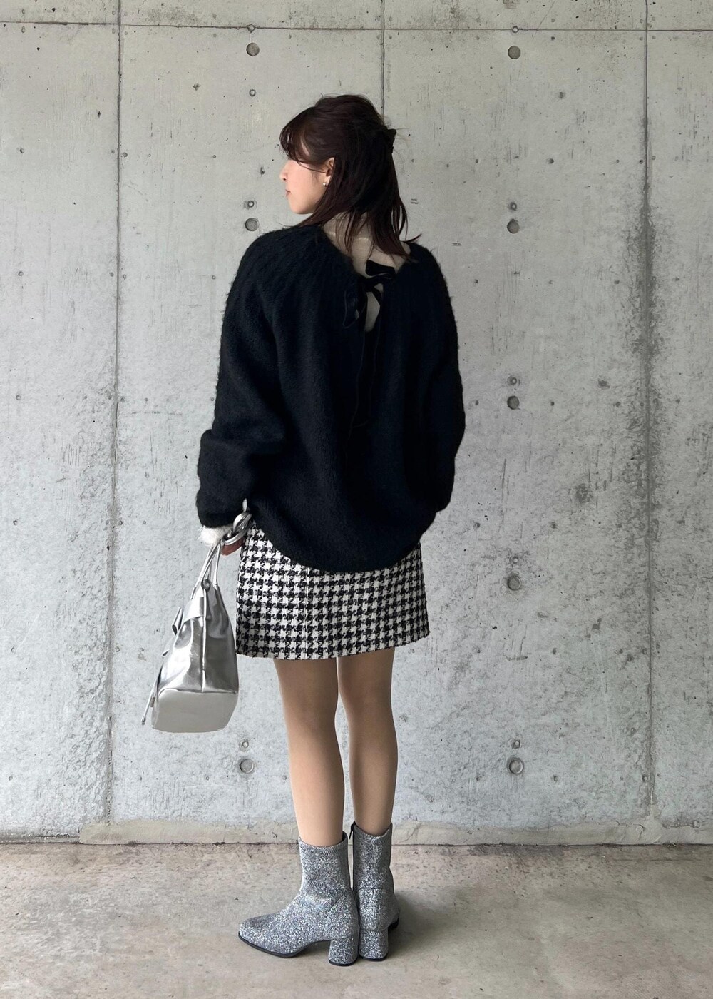 シルバー系のブーツ、ブラック系のスカート、ホワイト系のニット/セーターを着用したレディースの冬コーディネートの4枚目の写真