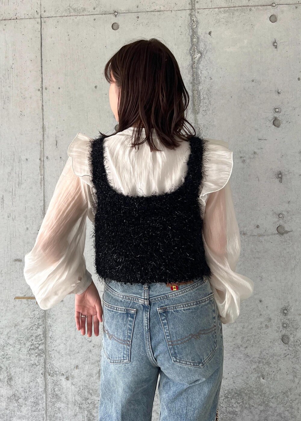 ブルー系のデニムパンツ、ブラック系のキャミソール、シルバー系のブーツを着用したレディースの秋コーディネートの9枚目の写真