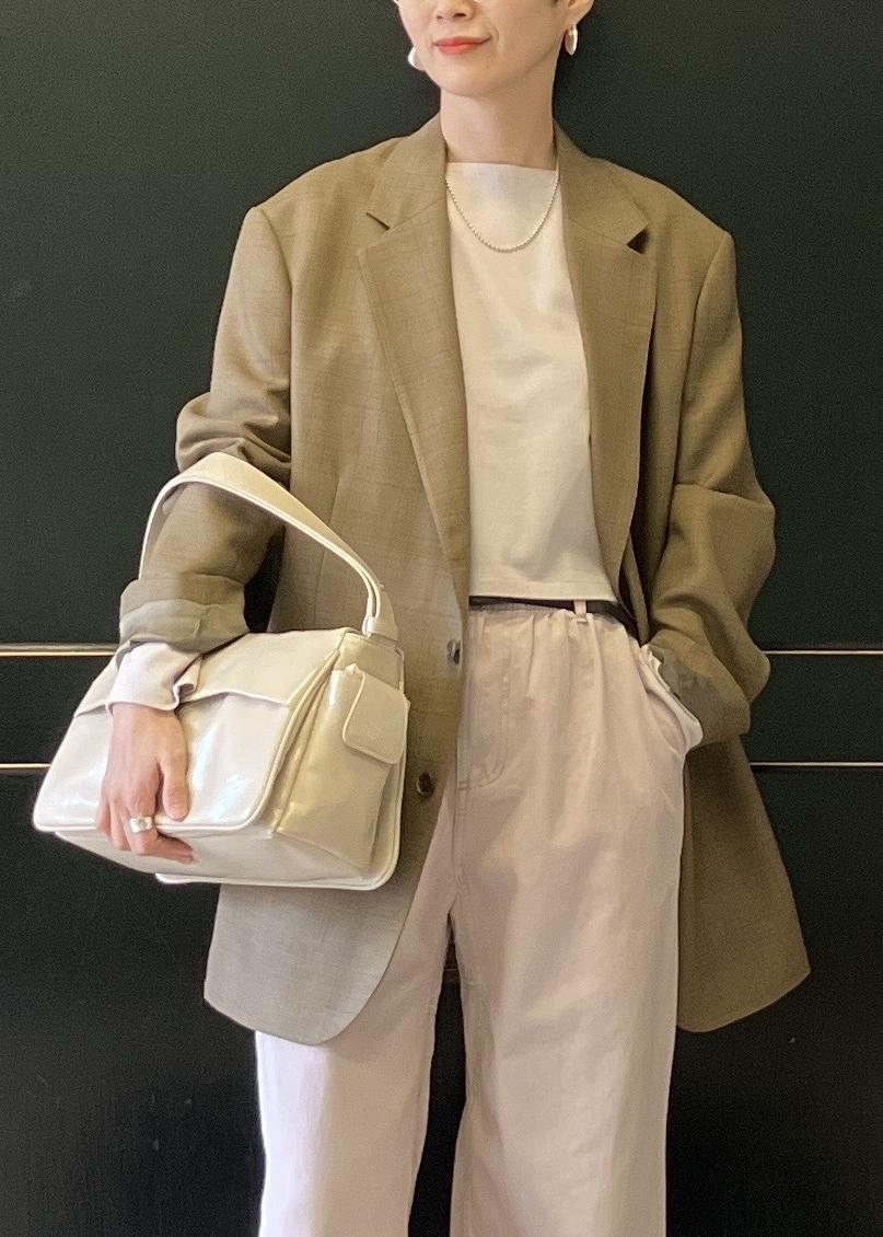 ベージュ系のショルダーバッグ、ホワイト系のパンプス、ピンク系のチノパンツを着用したレディースの冬コーディネートの4枚目の写真