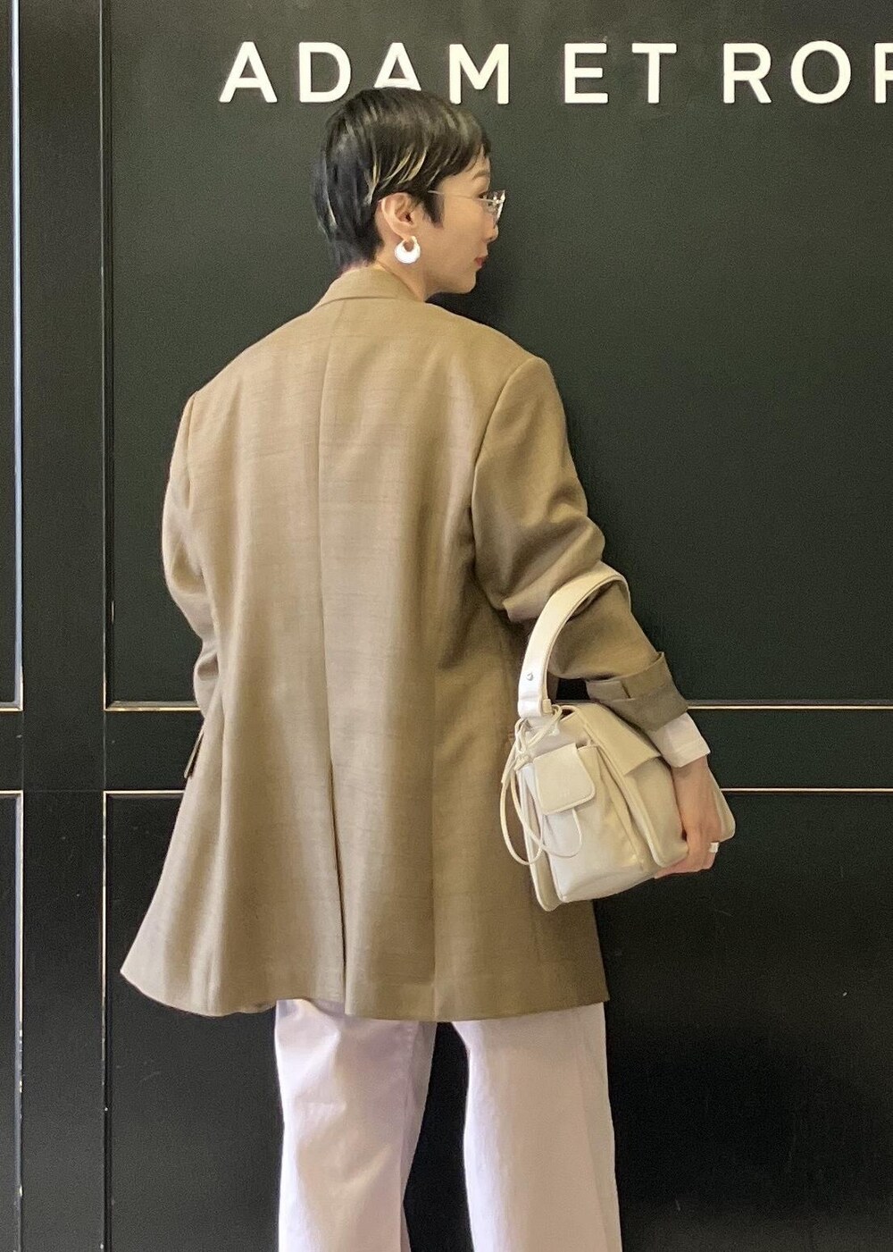 ベージュ系のショルダーバッグ、ホワイト系のパンプス、ピンク系のチノパンツを着用したレディースの冬コーディネートの6枚目の写真