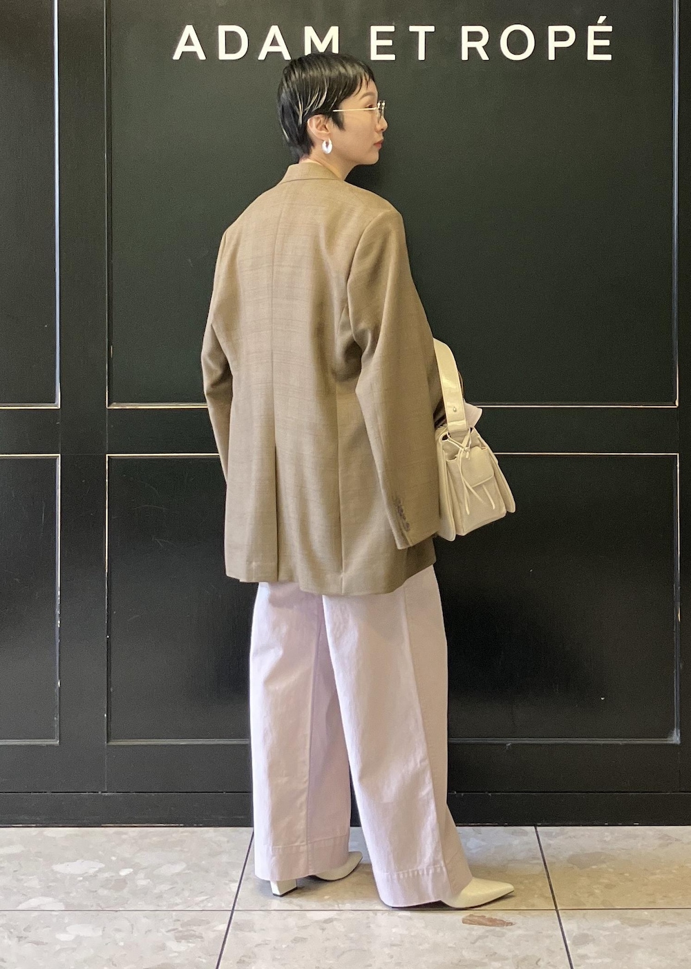 ベージュ系のショルダーバッグ、ホワイト系のパンプス、ピンク系のチノパンツを着用したレディースの冬コーディネートの3枚目の写真