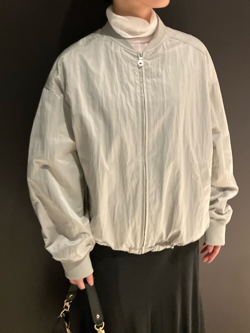 ベージュ系のブルゾン、ブラック系のハンドバッグ、ホワイト系のTシャツ/カットソーを着用したレディースの春コーディネートの2枚目の写真