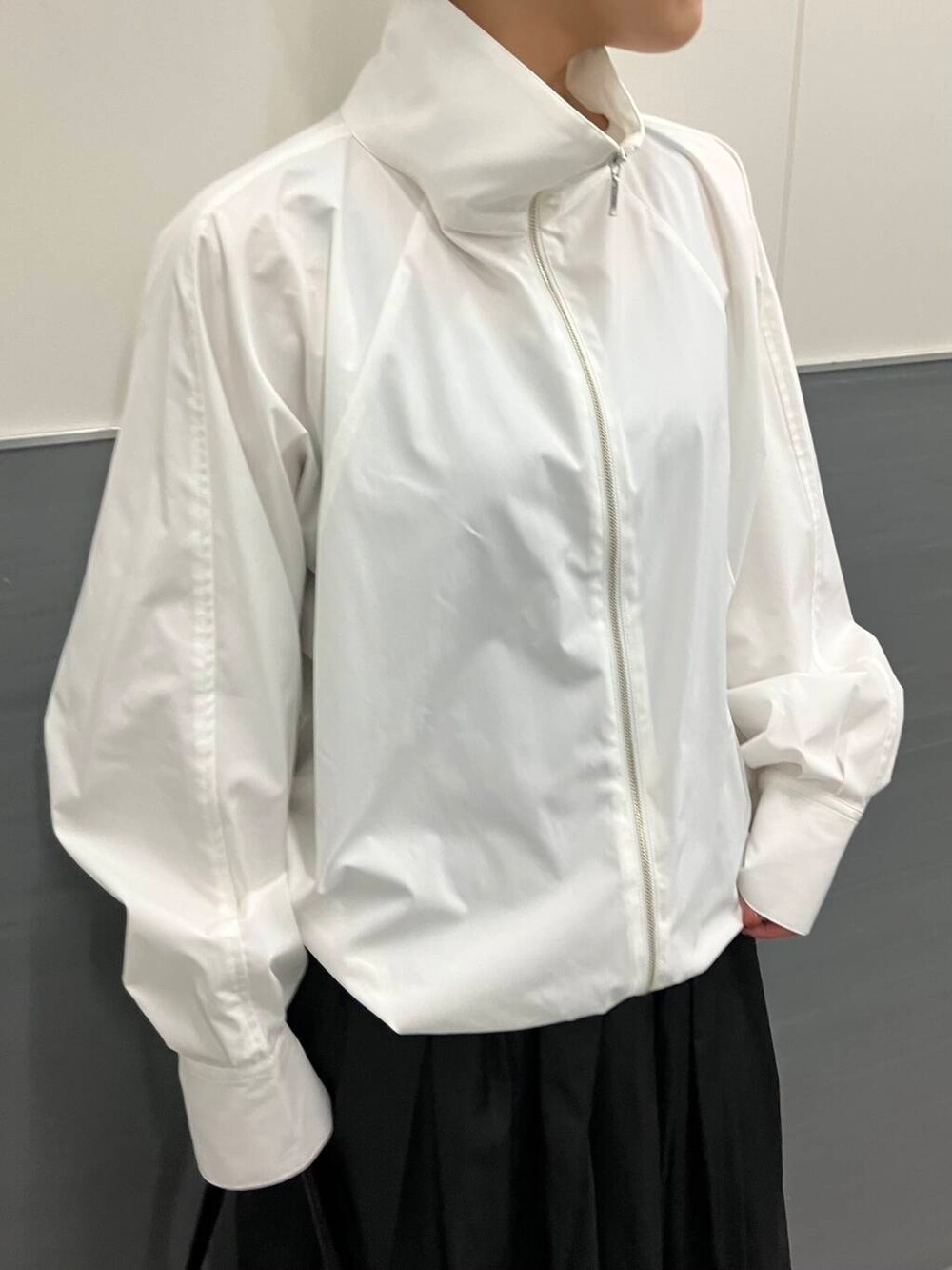 ホワイト系のスニーカー、ブラック系のスカート、ホワイト系のブルゾンを着用したレディースの秋コーディネートの5枚目の写真