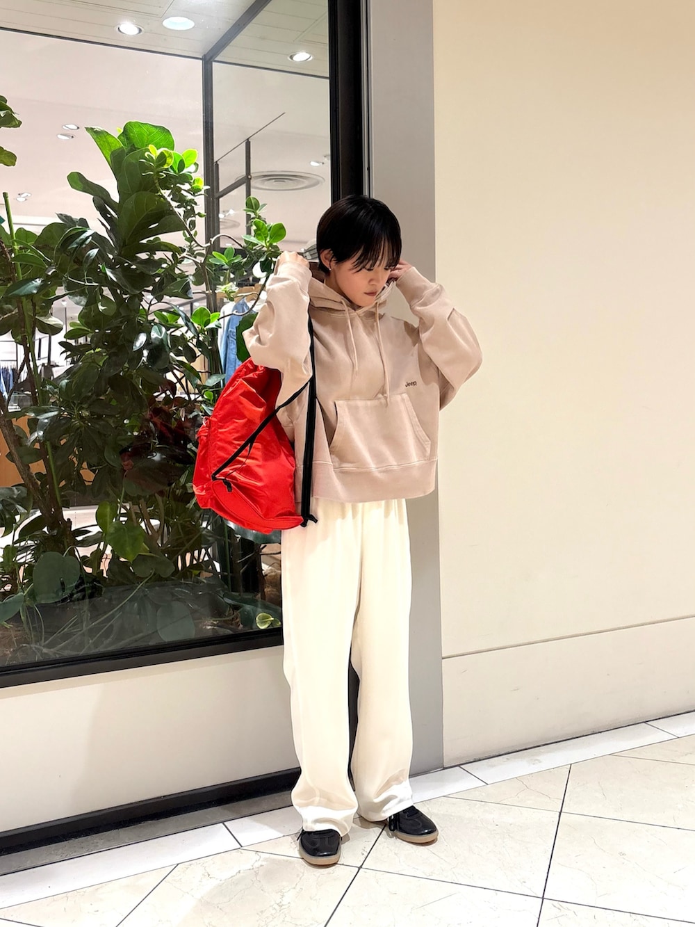 ベージュ系のパーカー、ホワイト系のその他パンツ、レッド系のバックパック/リュックを着用したレディースの冬コーディネートの2枚目の写真