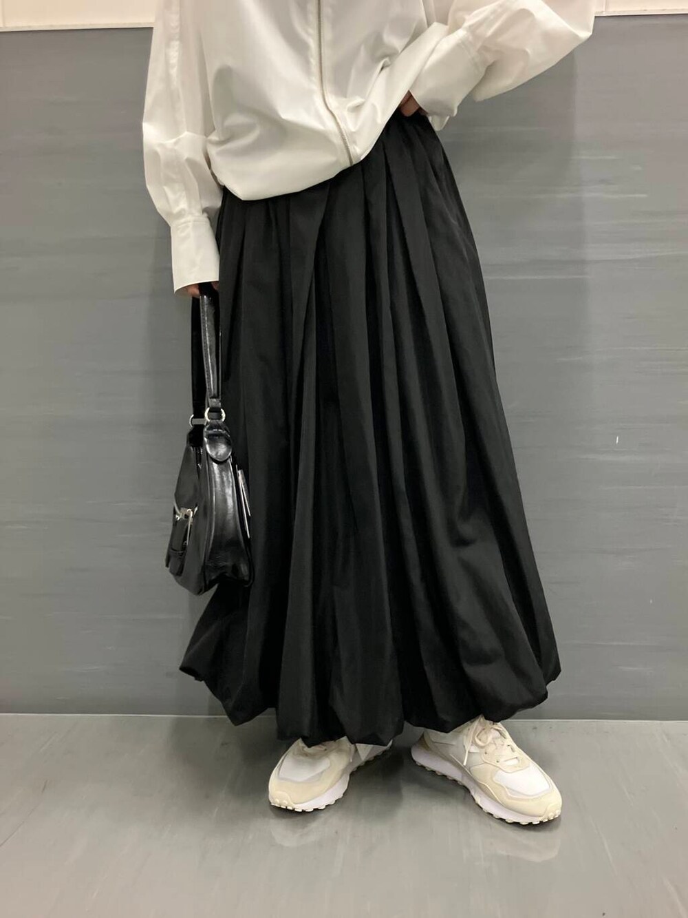 ホワイト系のスニーカー、ブラック系のスカート、ホワイト系のブルゾンを着用したレディースの秋コーディネートの6枚目の写真