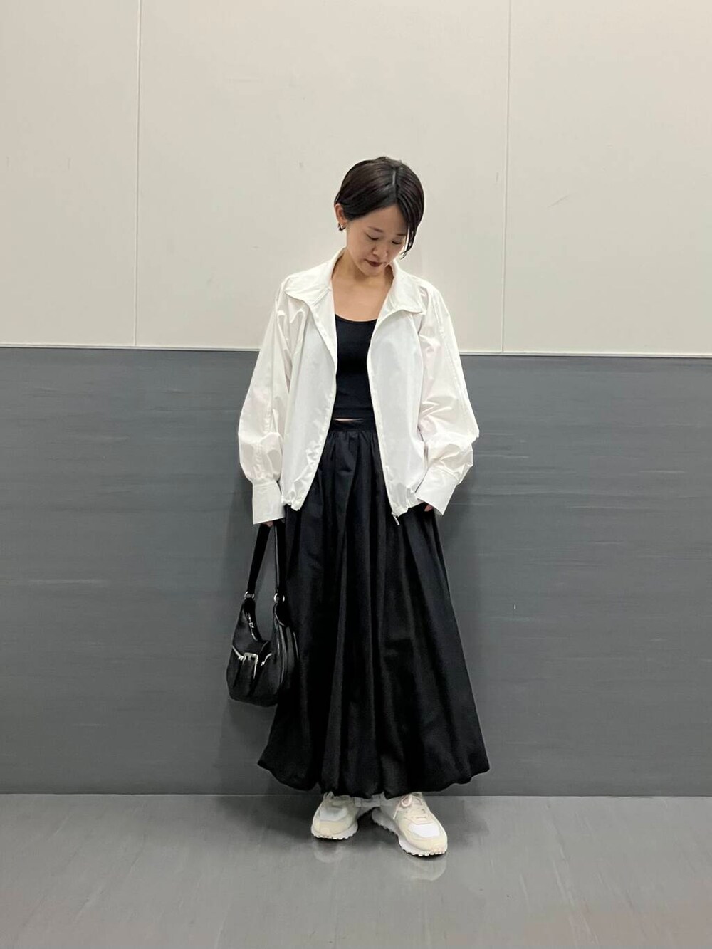 ホワイト系のスニーカー、ブラック系のスカート、ホワイト系のブルゾンを着用したレディースの秋コーディネートの4枚目の写真