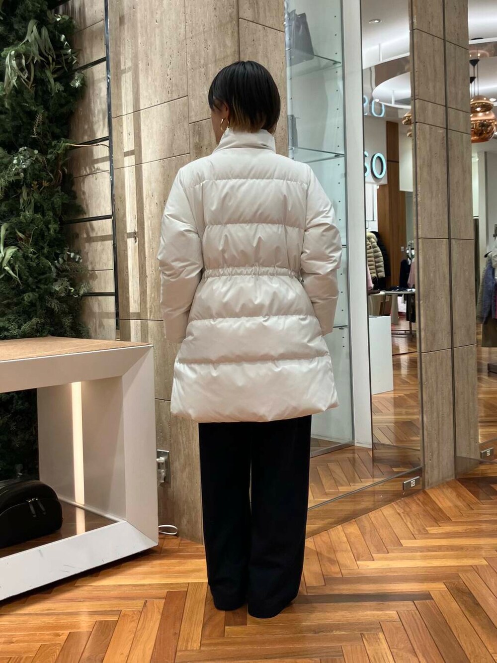 ホワイト系のダウンジャケット/コート、オレンジ系のニット/セーター、ブラック系のその他パンツを着用したレディースの冬コーディネートの4枚目の写真