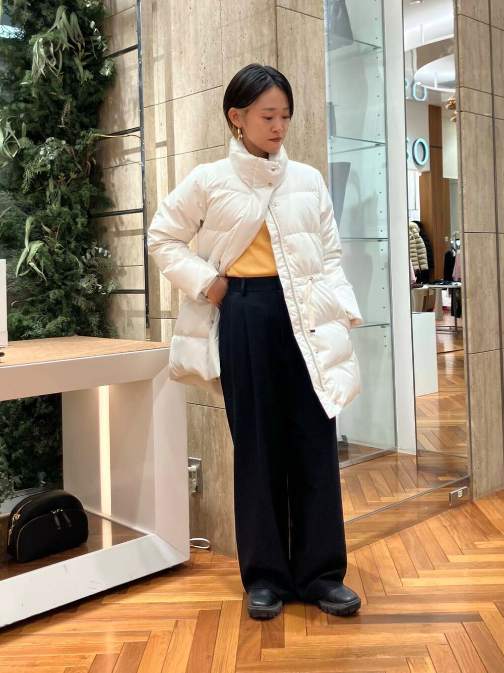 ホワイト系のダウンジャケット/コート、オレンジ系のニット/セーター、ブラック系のその他パンツを着用したレディースの冬コーディネートの2枚目の写真