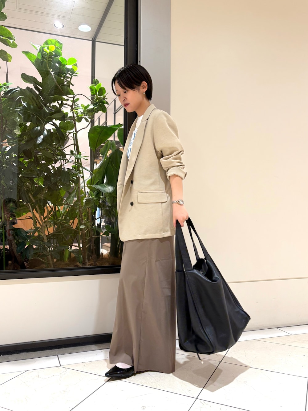 グレー系のスカート、ブルー系のTシャツ/カットソー、ベージュ系のその他アウターを着用したレディースの春コーディネートの2枚目の写真