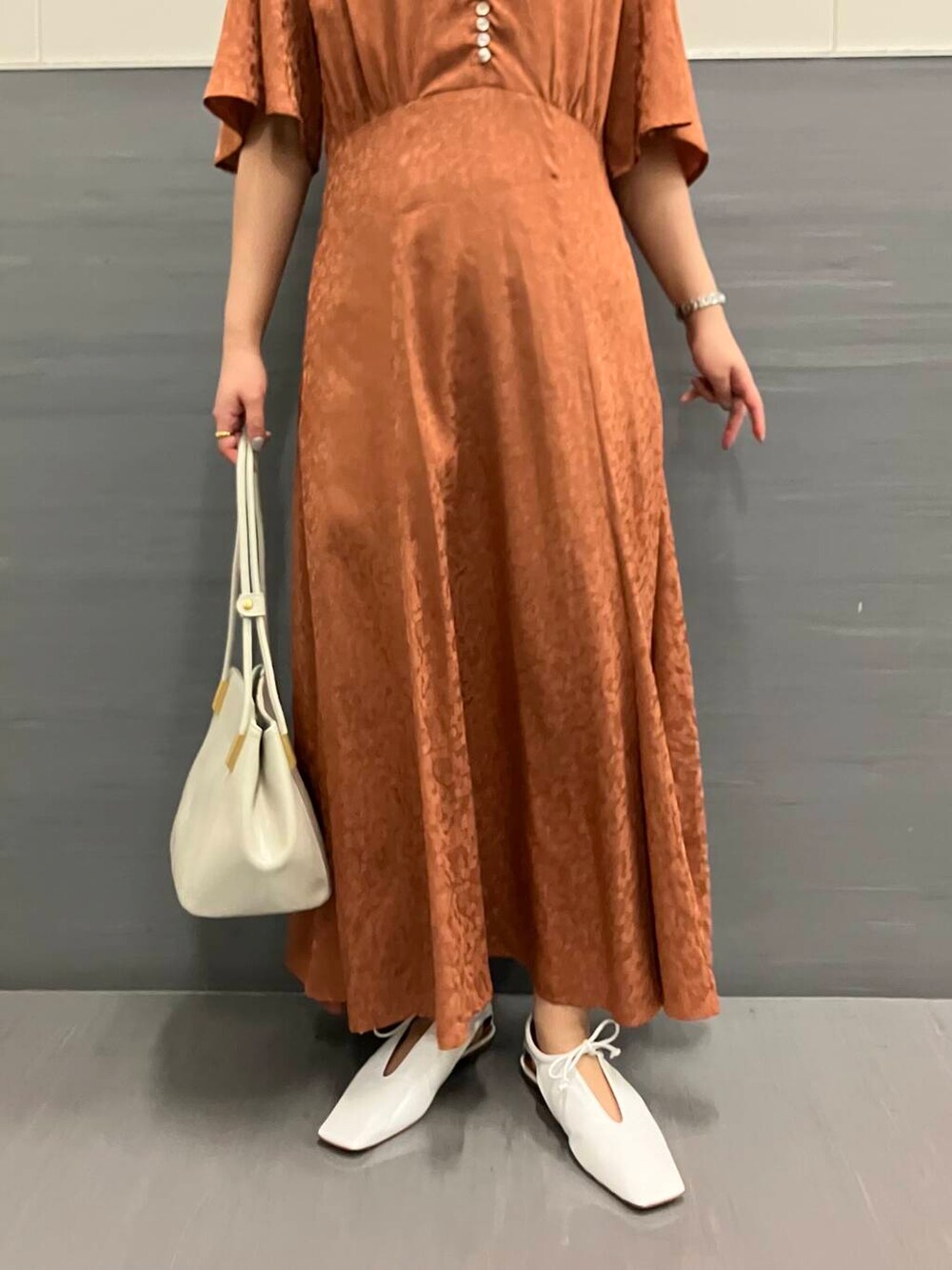 オレンジ系のワンピース、ホワイト系のトートバッグ、ホワイト系のその他シューズを着用したレディースの夏コーディネートの3枚目の写真