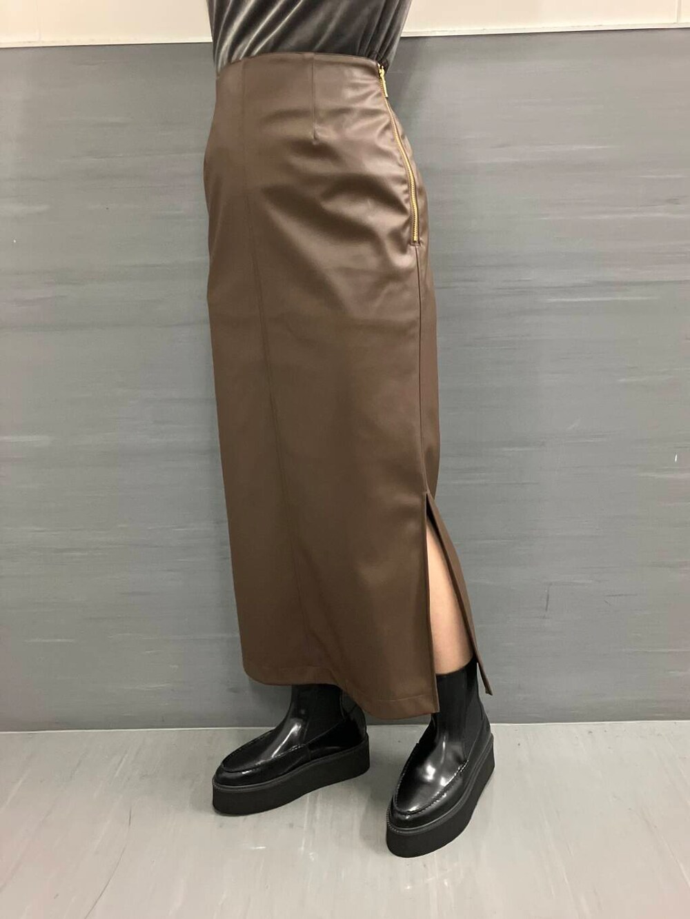 ブラウン系のスカート、グレー系のTシャツ/カットソー、ブラック系のブーツを着用したレディースの秋コーディネートの5枚目の写真