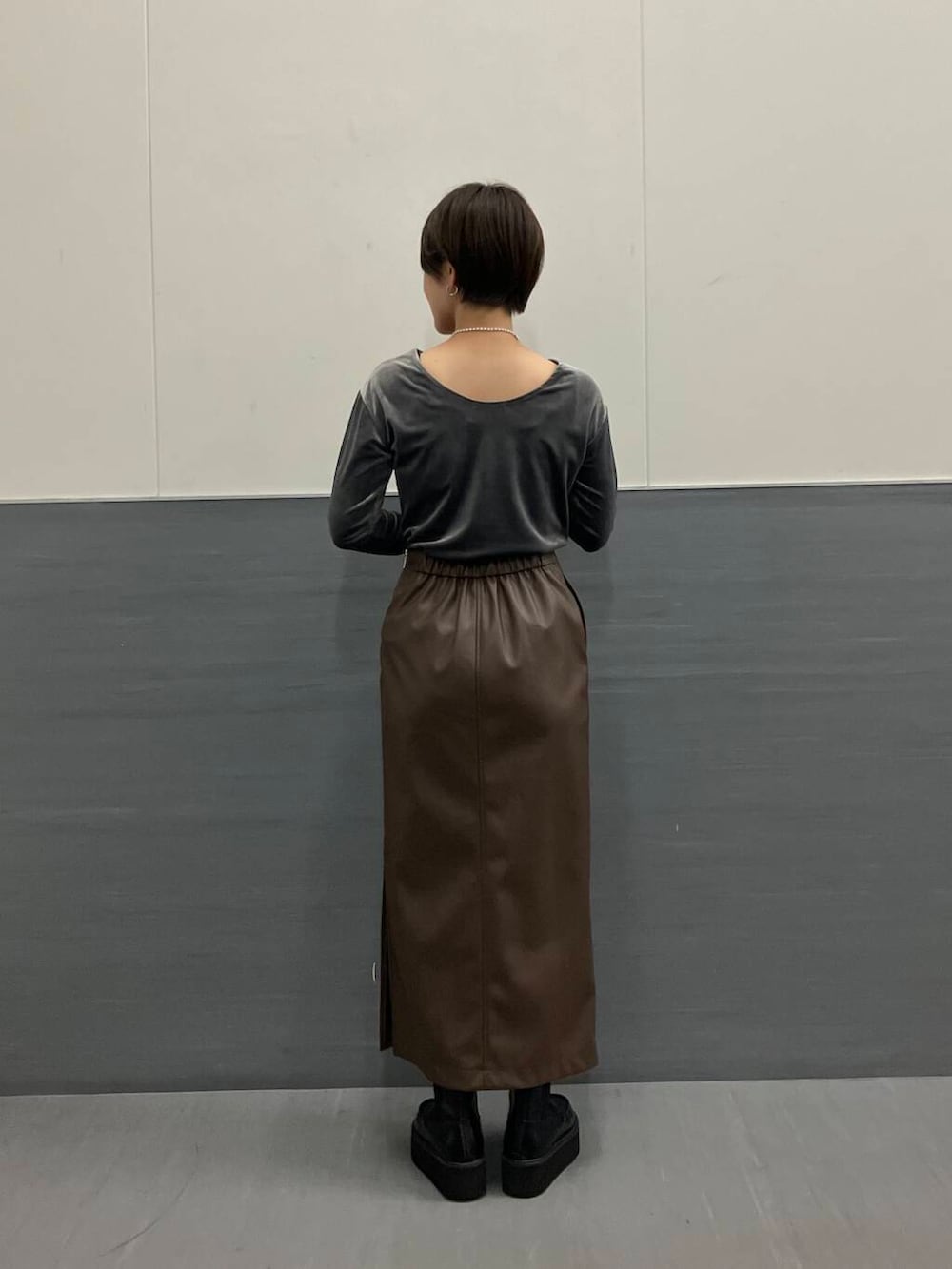 ブラウン系のスカート、グレー系のTシャツ/カットソー、ブラック系のブーツを着用したレディースの秋コーディネートの2枚目の写真