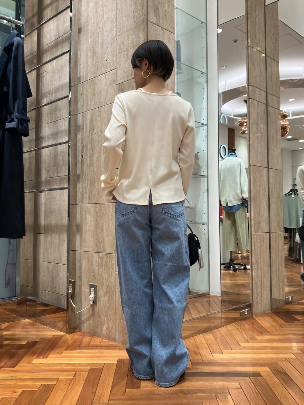 ブラック系のハンドバッグ、ホワイト系のTシャツ/カットソー、ブルー系のデニムパンツを着用したレディースの冬コーディネートの3枚目の写真